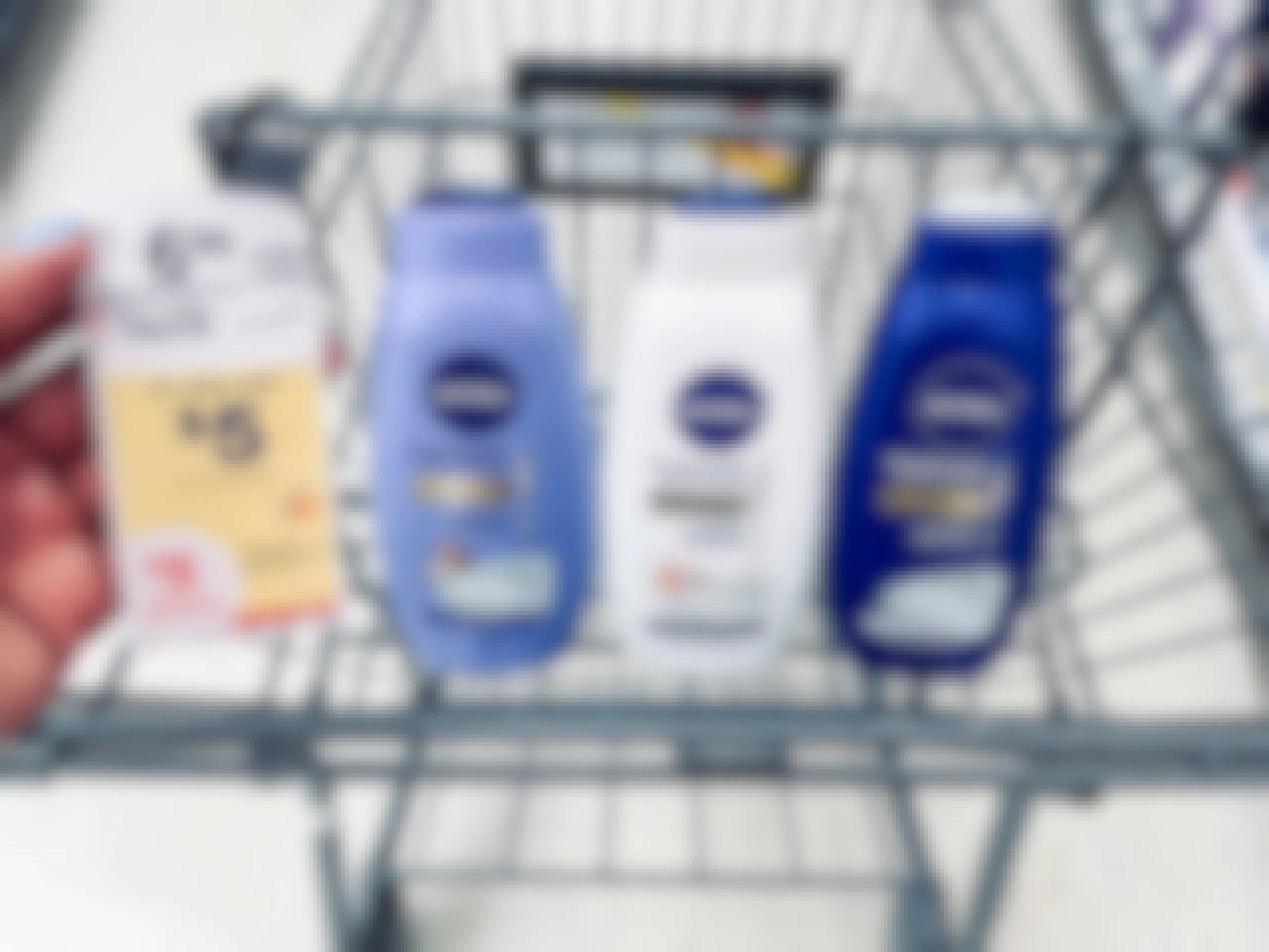 shopping cart with three bottles of Nivea body washes and hand holding sales tag in the air next to the bottles