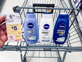 shopping cart with three bottles of Nivea body washes and hand holding sales tag in the air next to the bottles