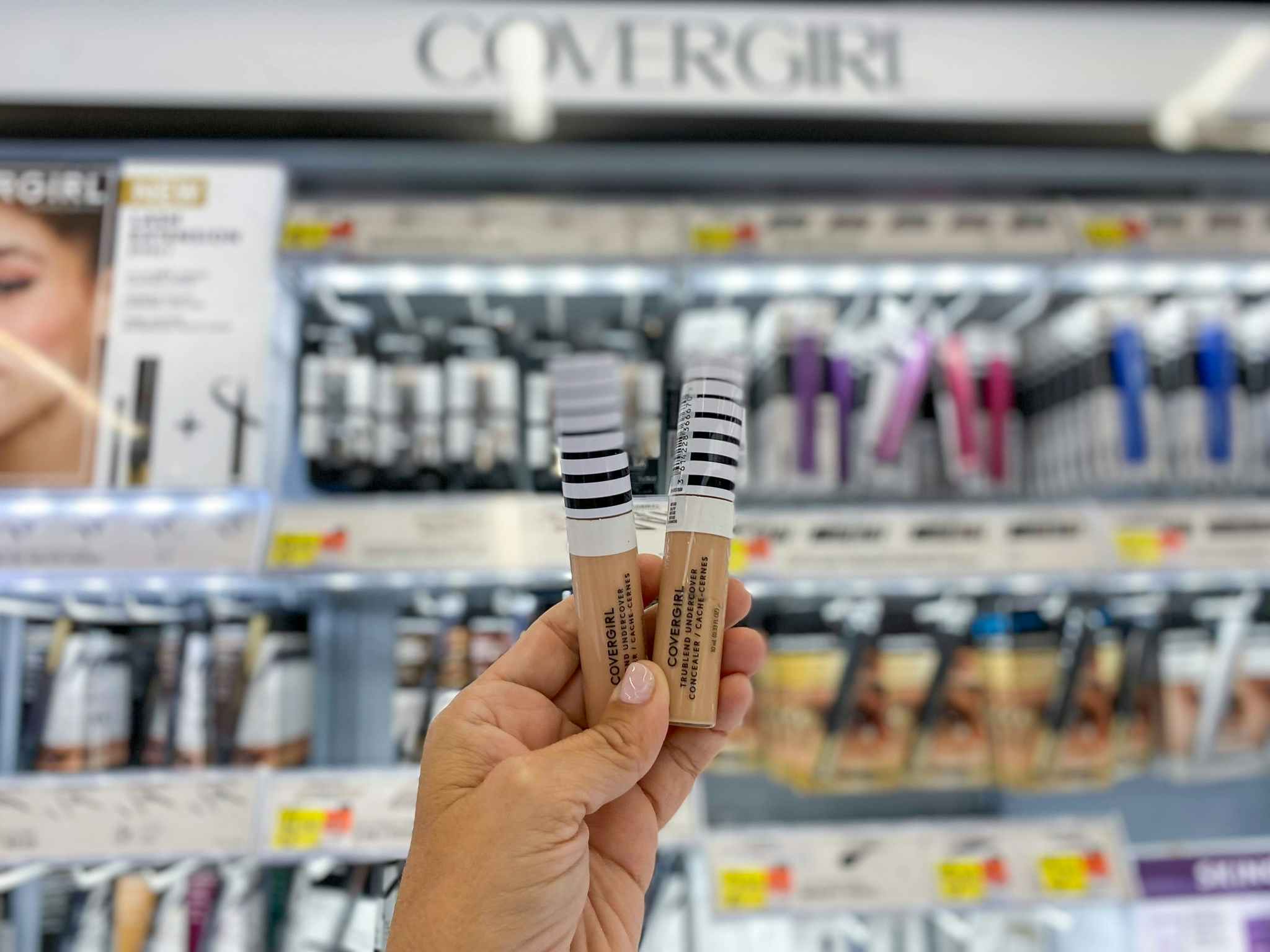 hand holding two covergirl trublend undercover concealer bottles at walmart