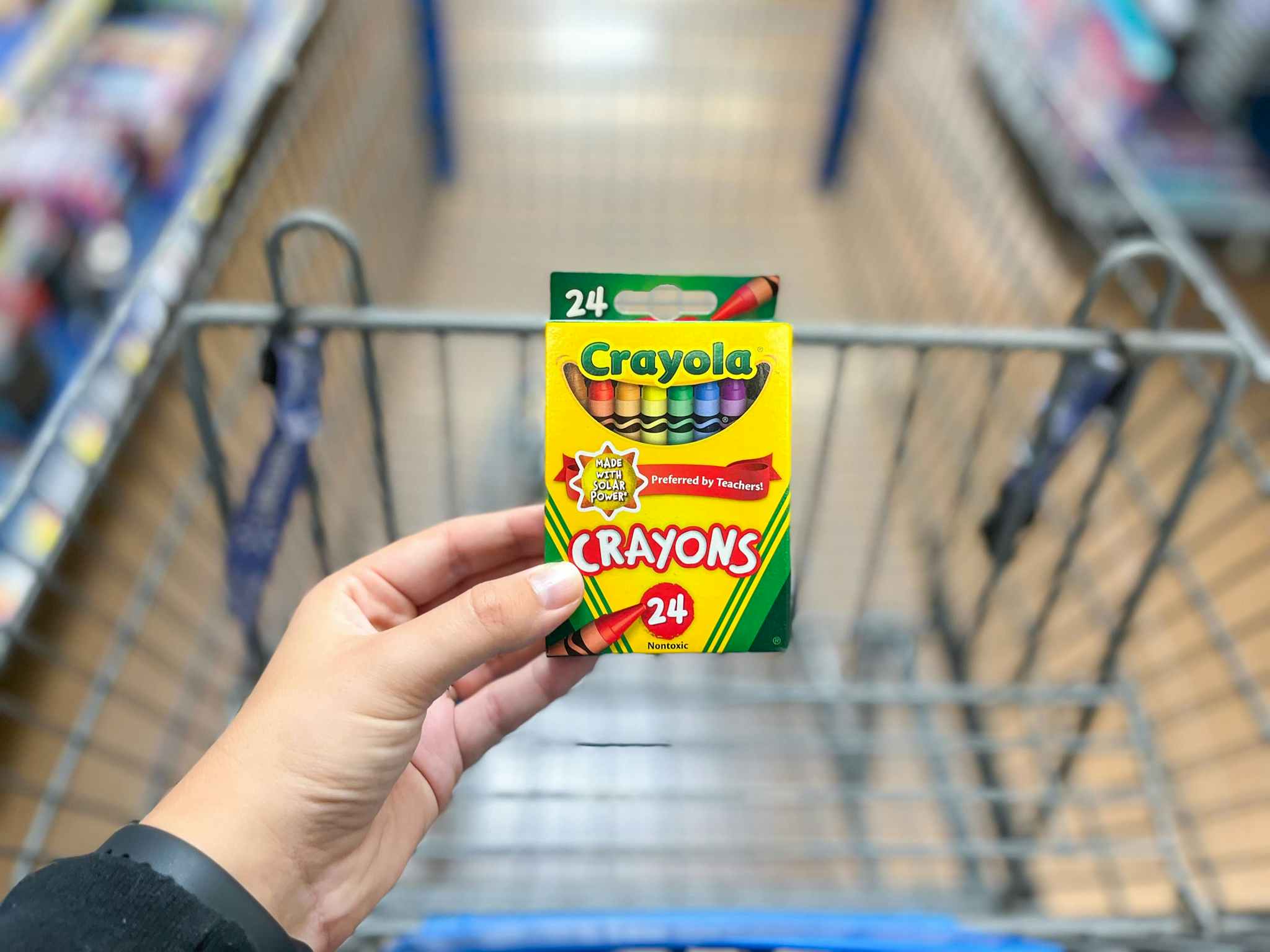 hand holding crayola crayons over cart at walmart