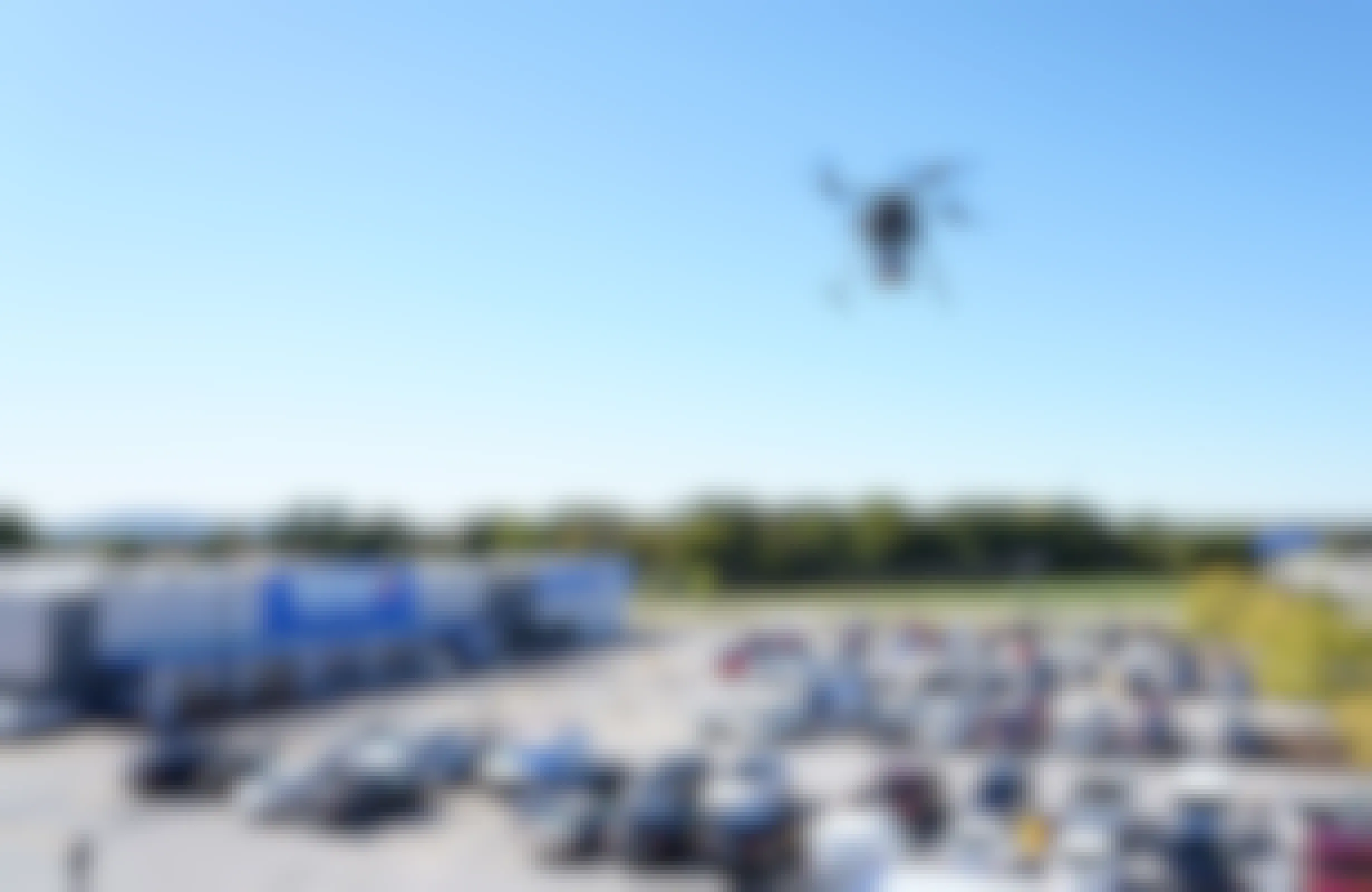A drone carrying a Walmart delivery box in the sky above a Walmart.