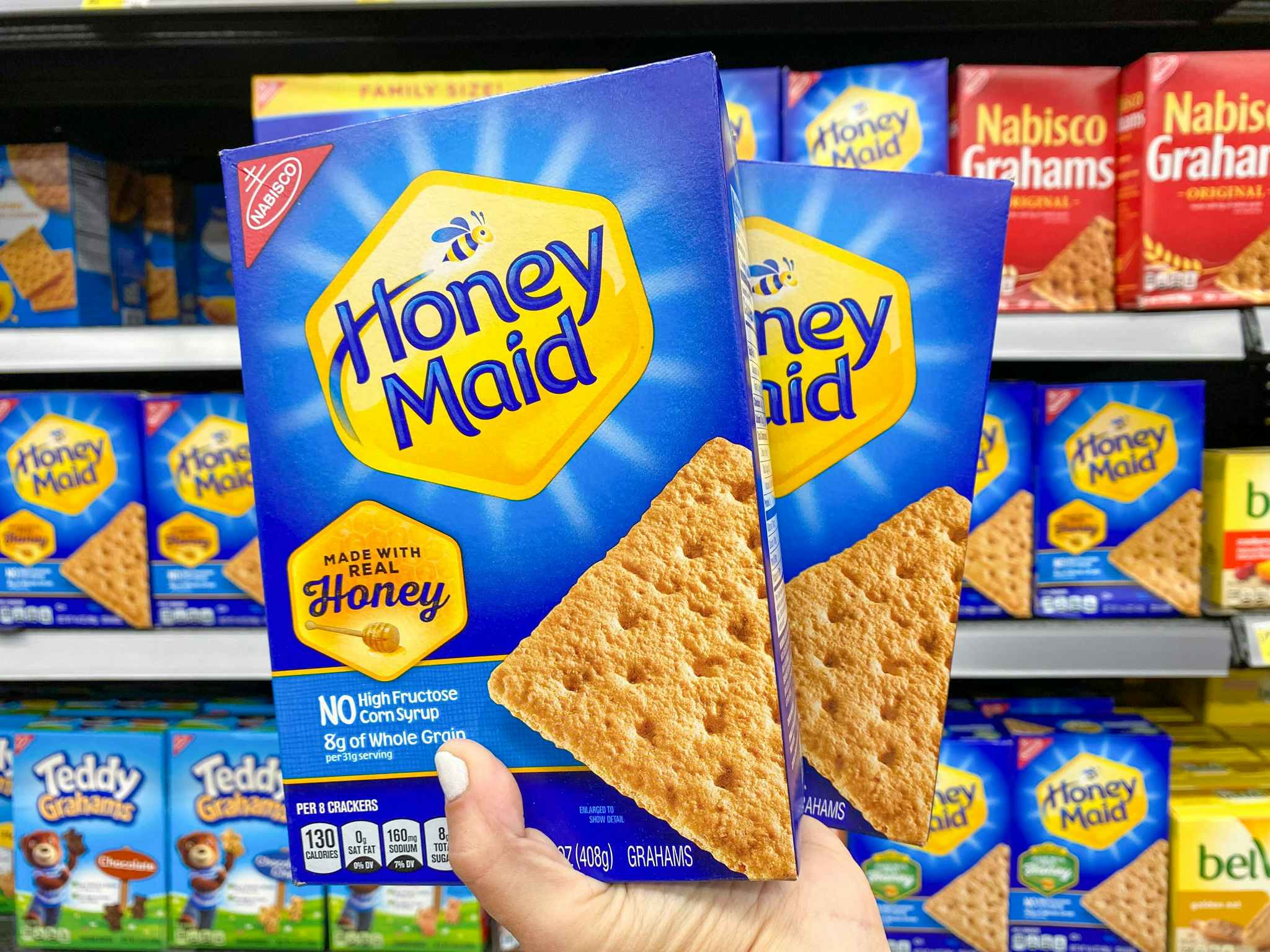 Two boxes of Honey Maid Grahm Crackers held in front of grahm cracker products at Walmart