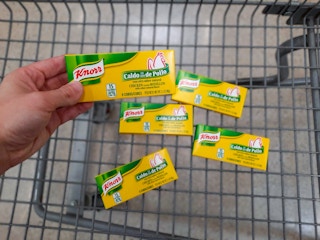 hand holding knorr bouillon cubes over walmart cart