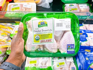 Hand holding Perdue Harvestland Chicken Drumsticks at Walmart