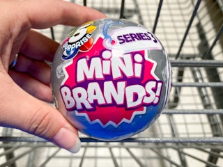 Zuru 5 Surprise Mini Brands Mystery Capsule held over Walmart shopping cart