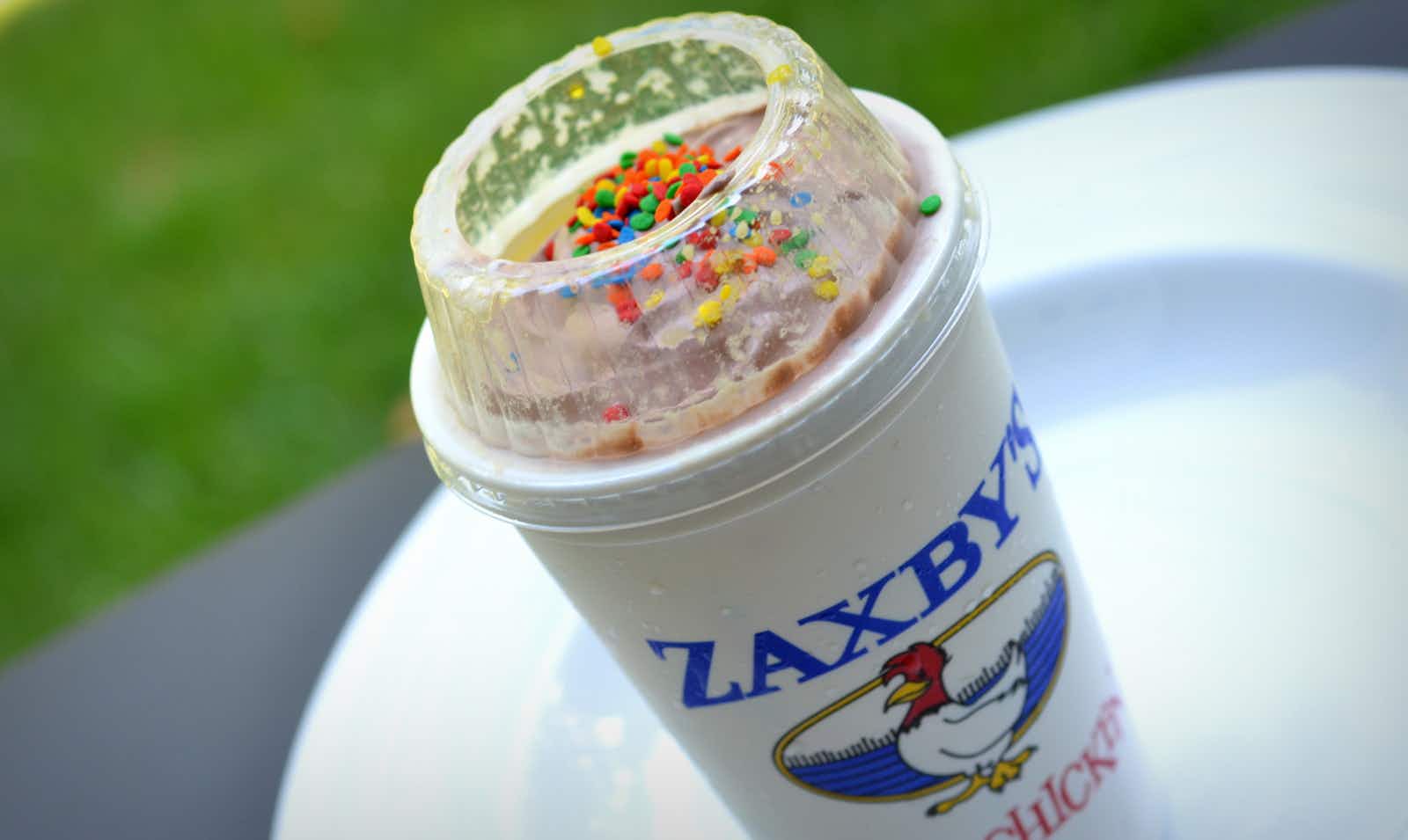 A Zaxby's milkshake with sprinkles on a table outside.