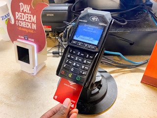 A person's hand inserting their credit card into the card reader at the counter of Zaxby's.