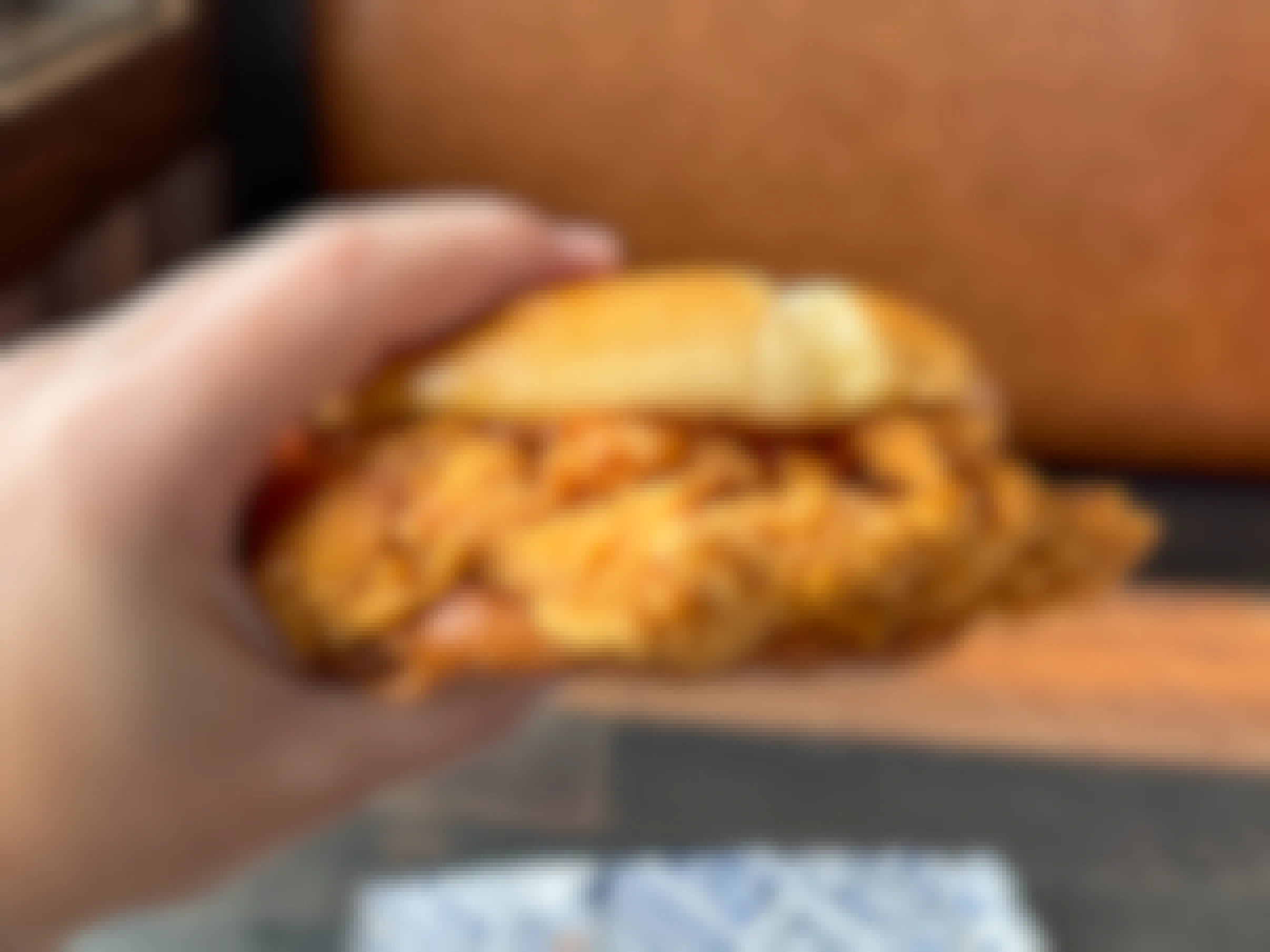A person's hand holding up a chicken sandwich from Zaxby's restaurant.