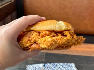 A person's hand holding up a chicken sandwich from Zaxby's restaurant.