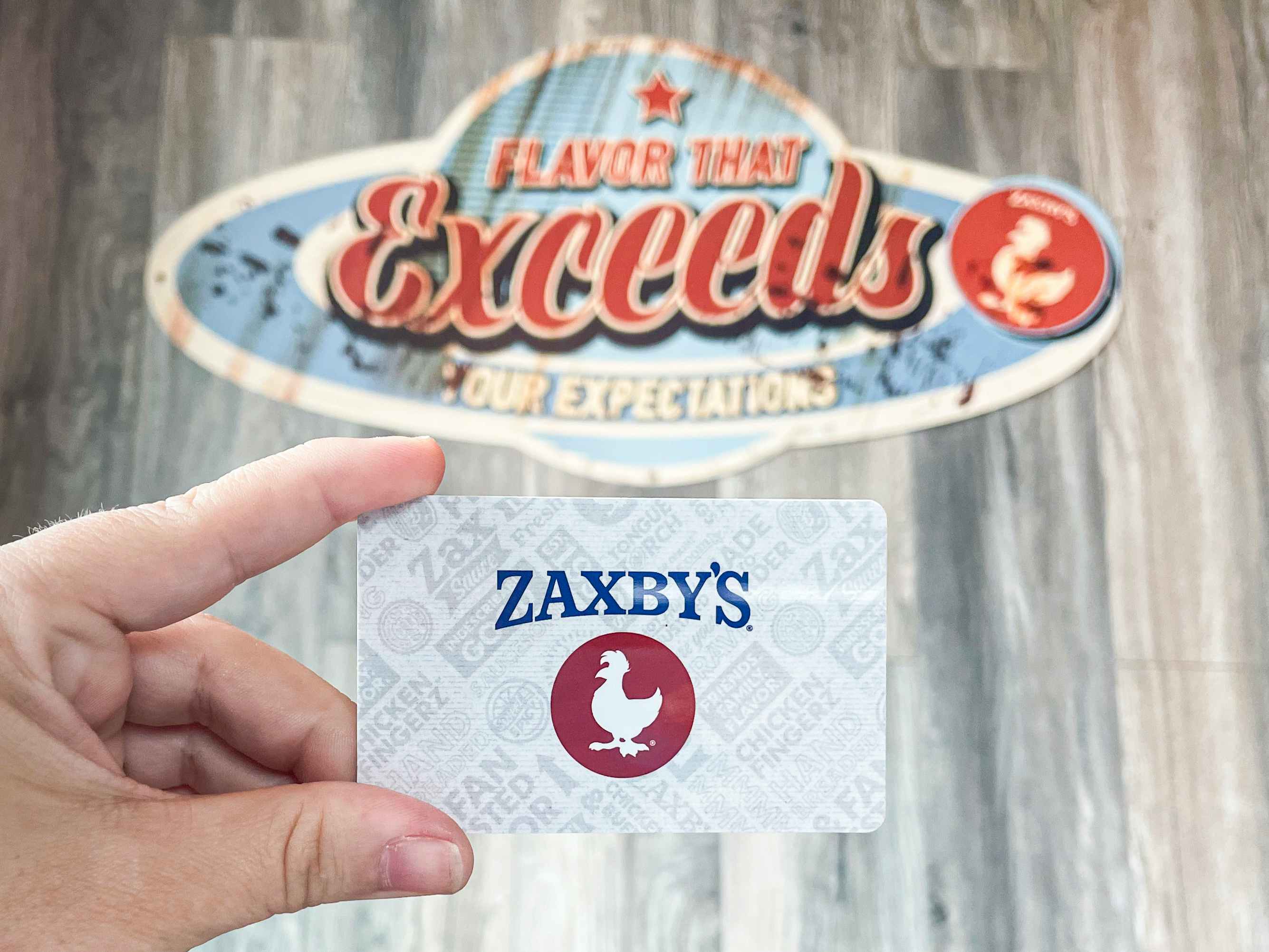 A person holding a Zaxby's gift card inside a Zaxby's restaurant.