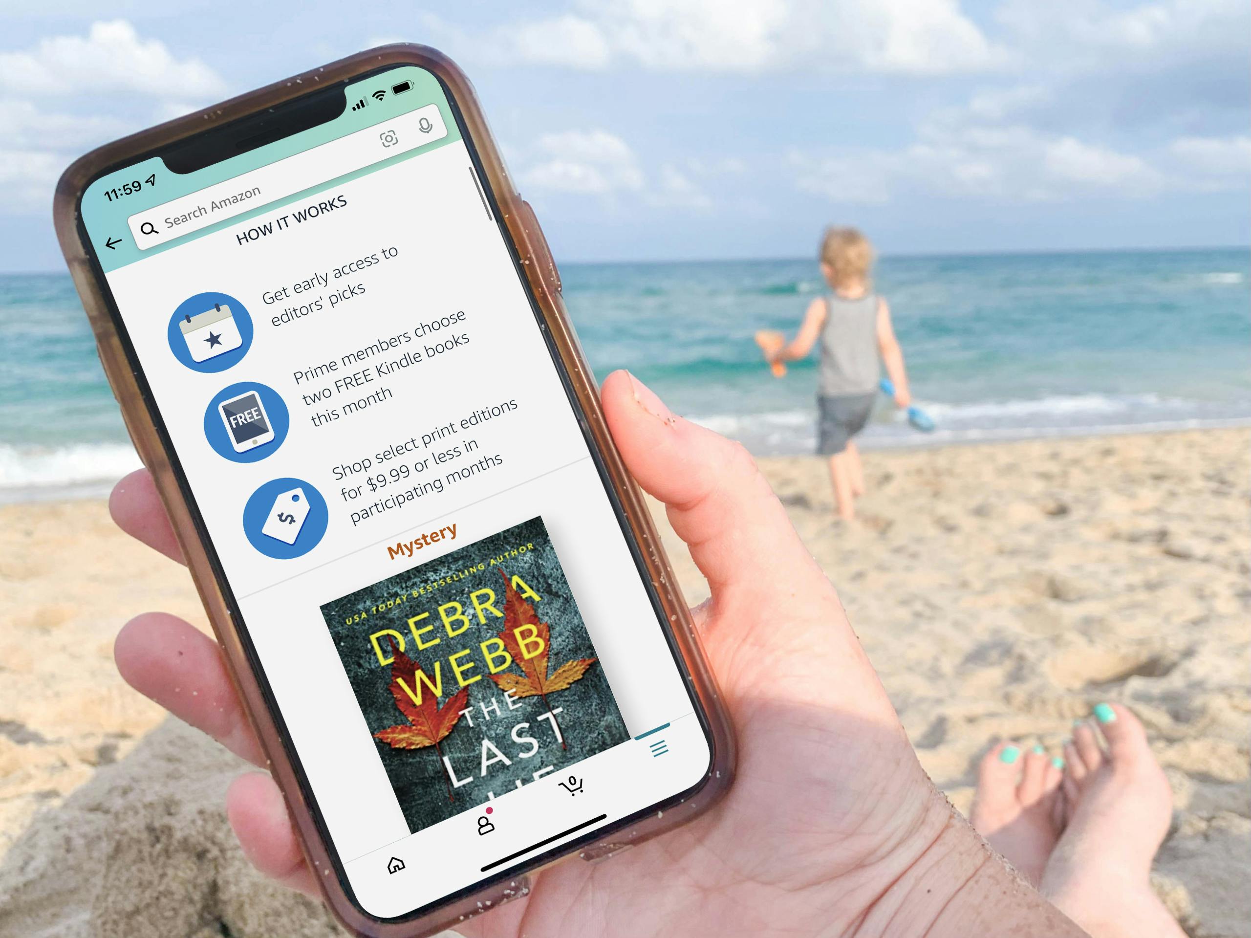 A person sitting on a beach holding a cell phone with the Amazon first reads app page open on her cell phone screen.