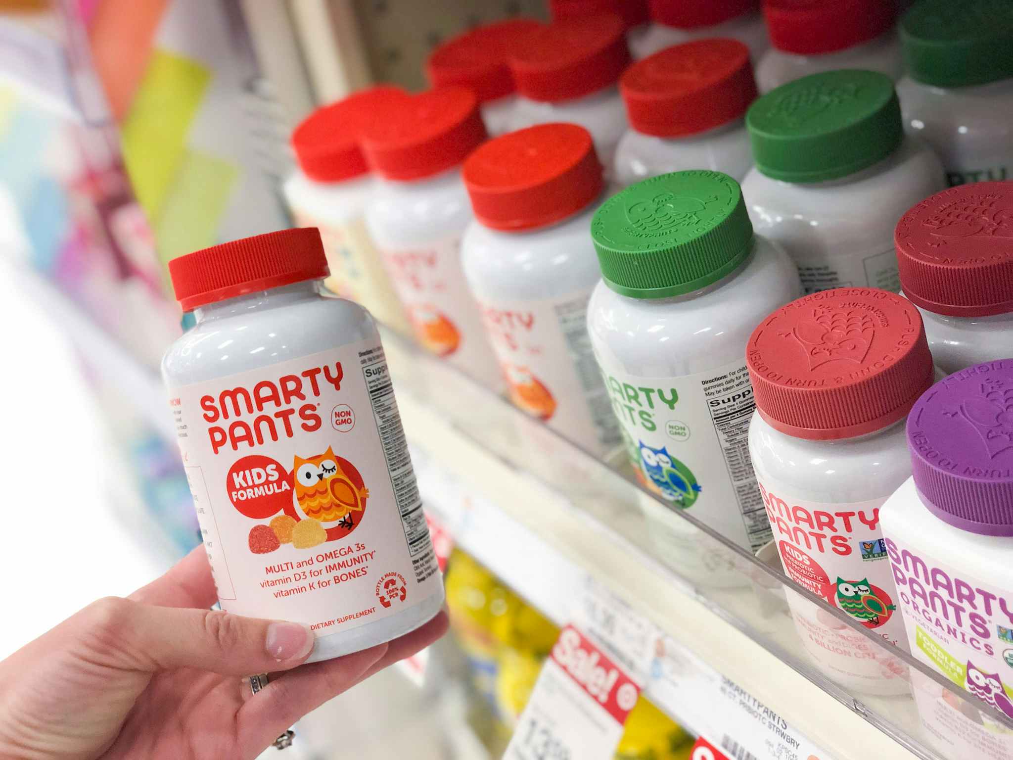 hand holding vitamin bottle in front of shelf at target