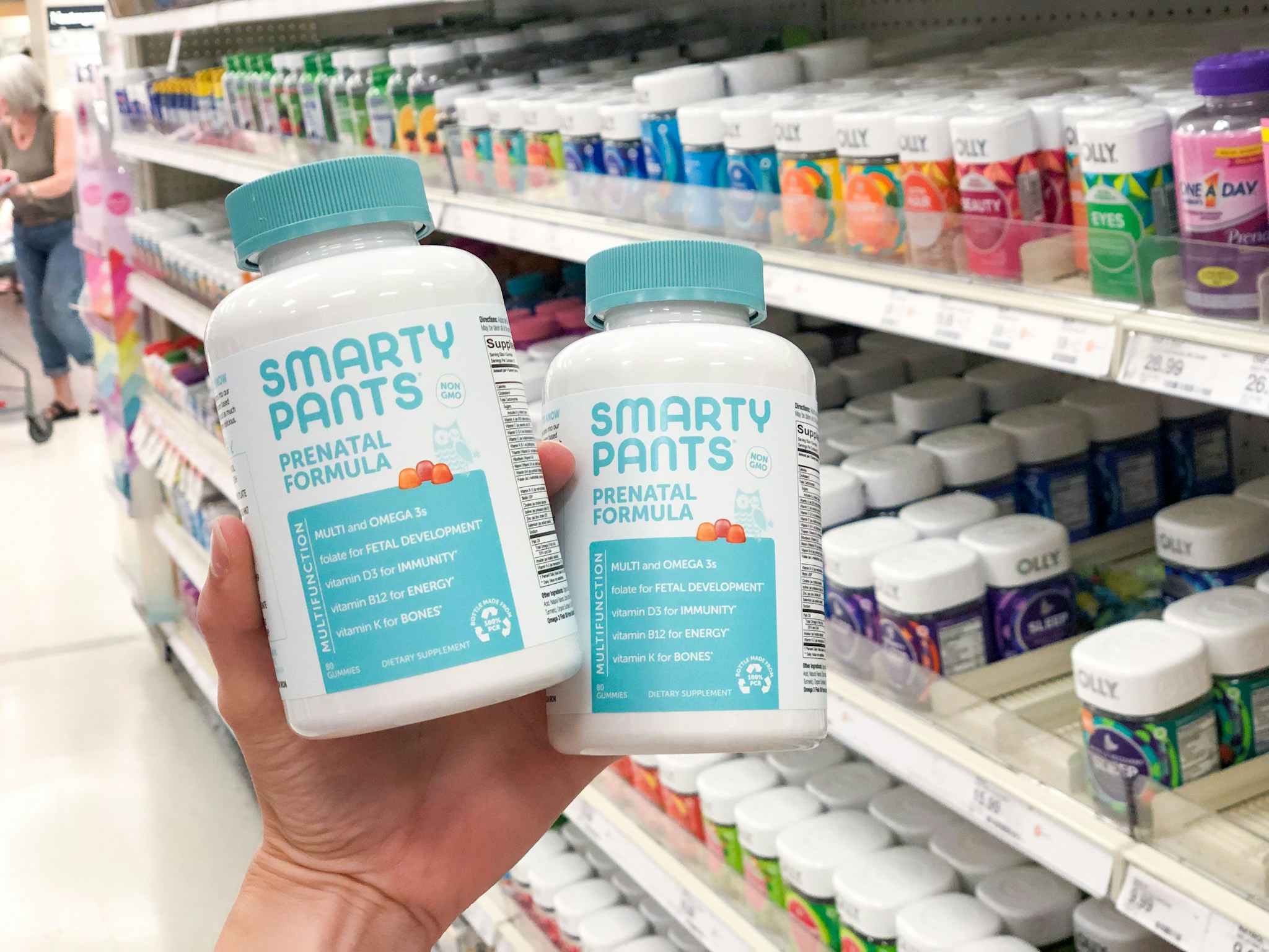 hand holding two vitamin bottles in front of shelf at target
