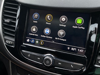 A close-up on a dashboard screen with Apple Car Play highlighted to activate.