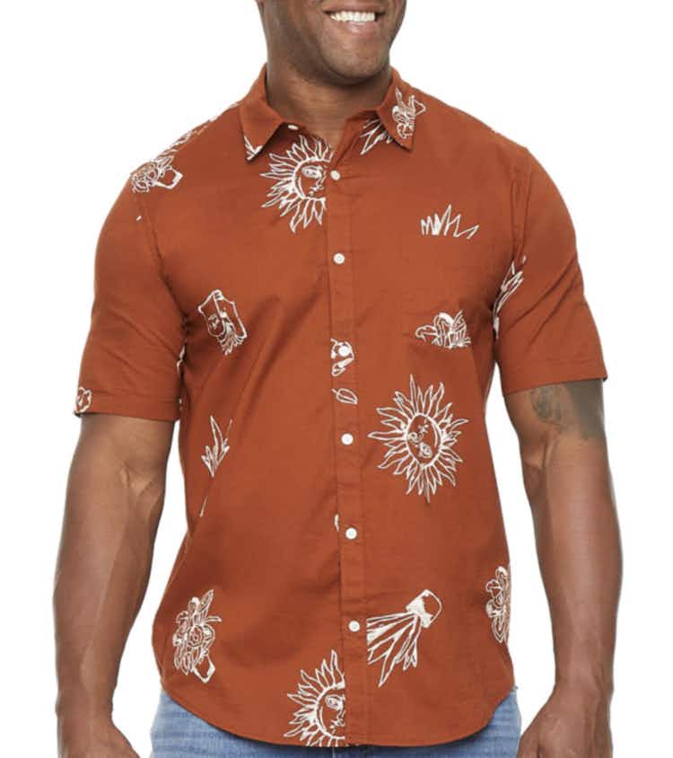 a man wearing a burnt orange button down shirt with white flowes