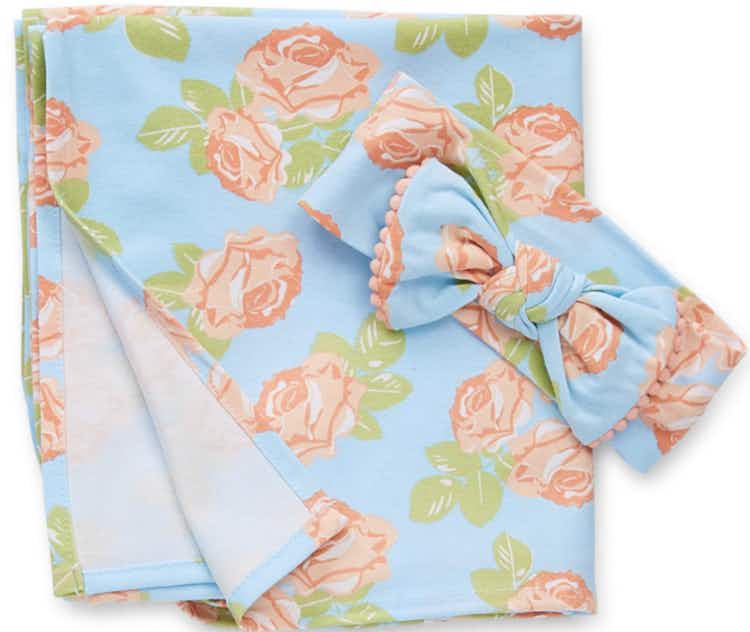 a baby girls blue swaddle with peach flowers and a matching headband