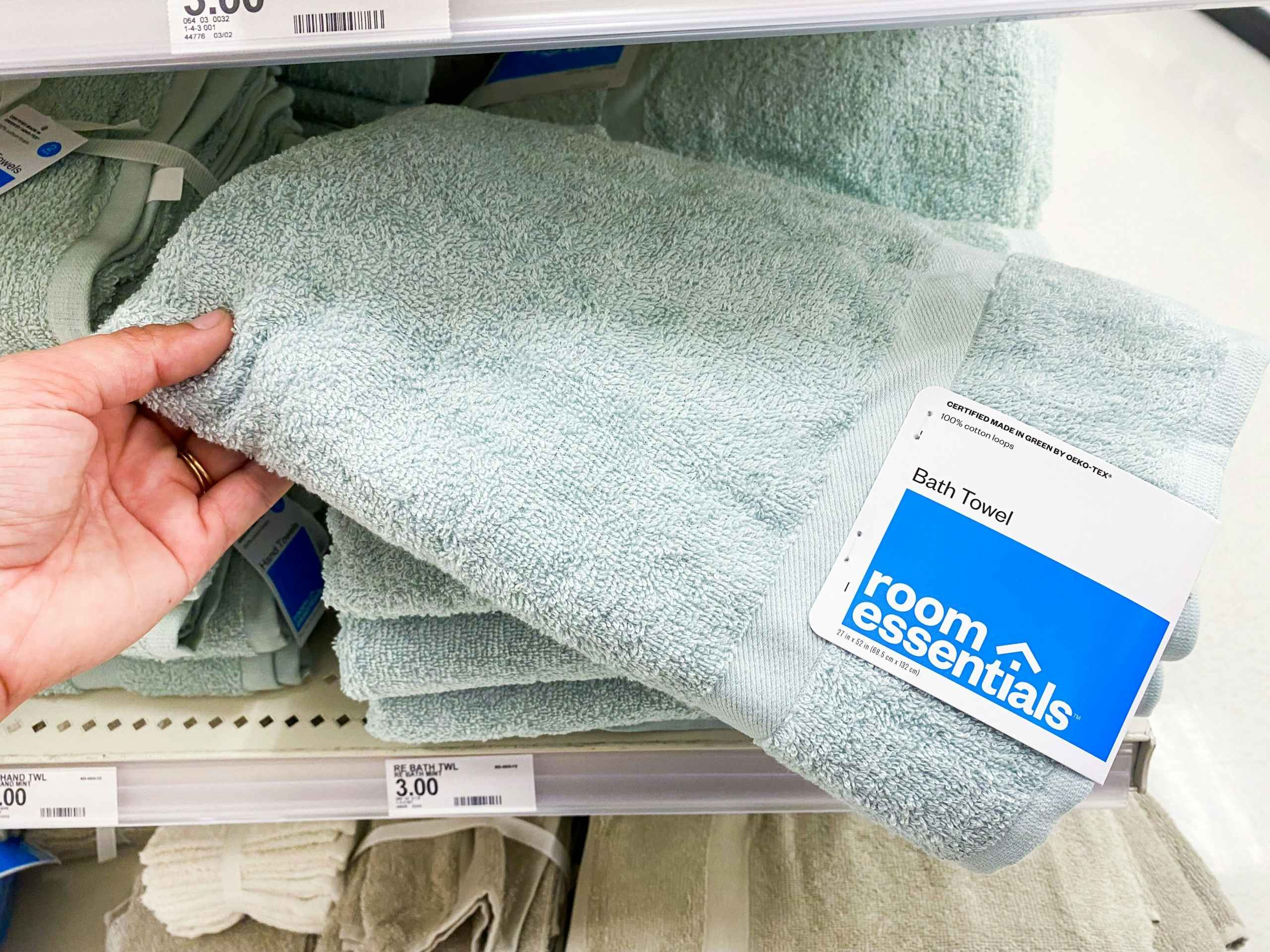 A hand holding a Room Essentials bath towel in Target