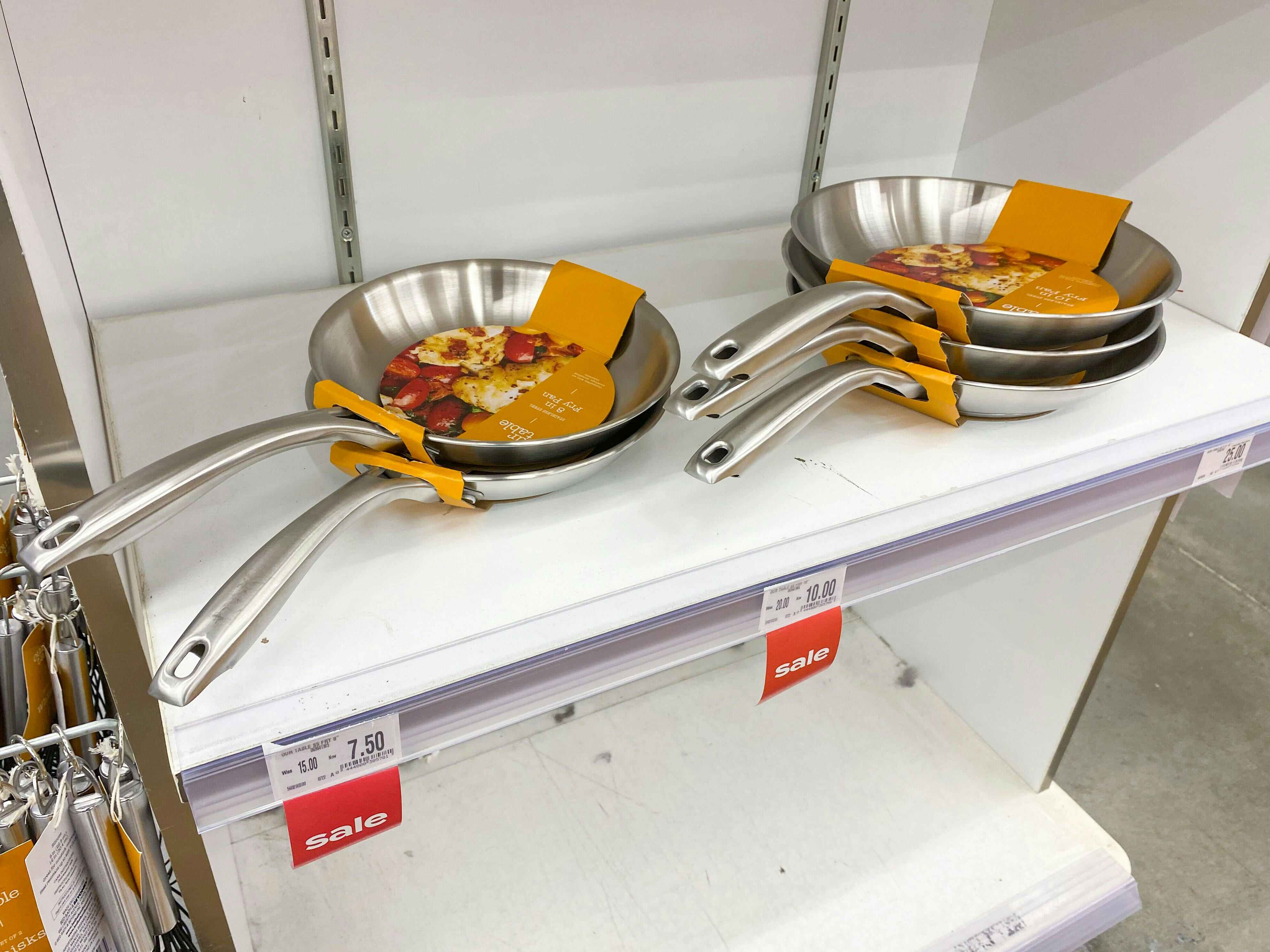 stainless steel fry pan on white shelf at angle