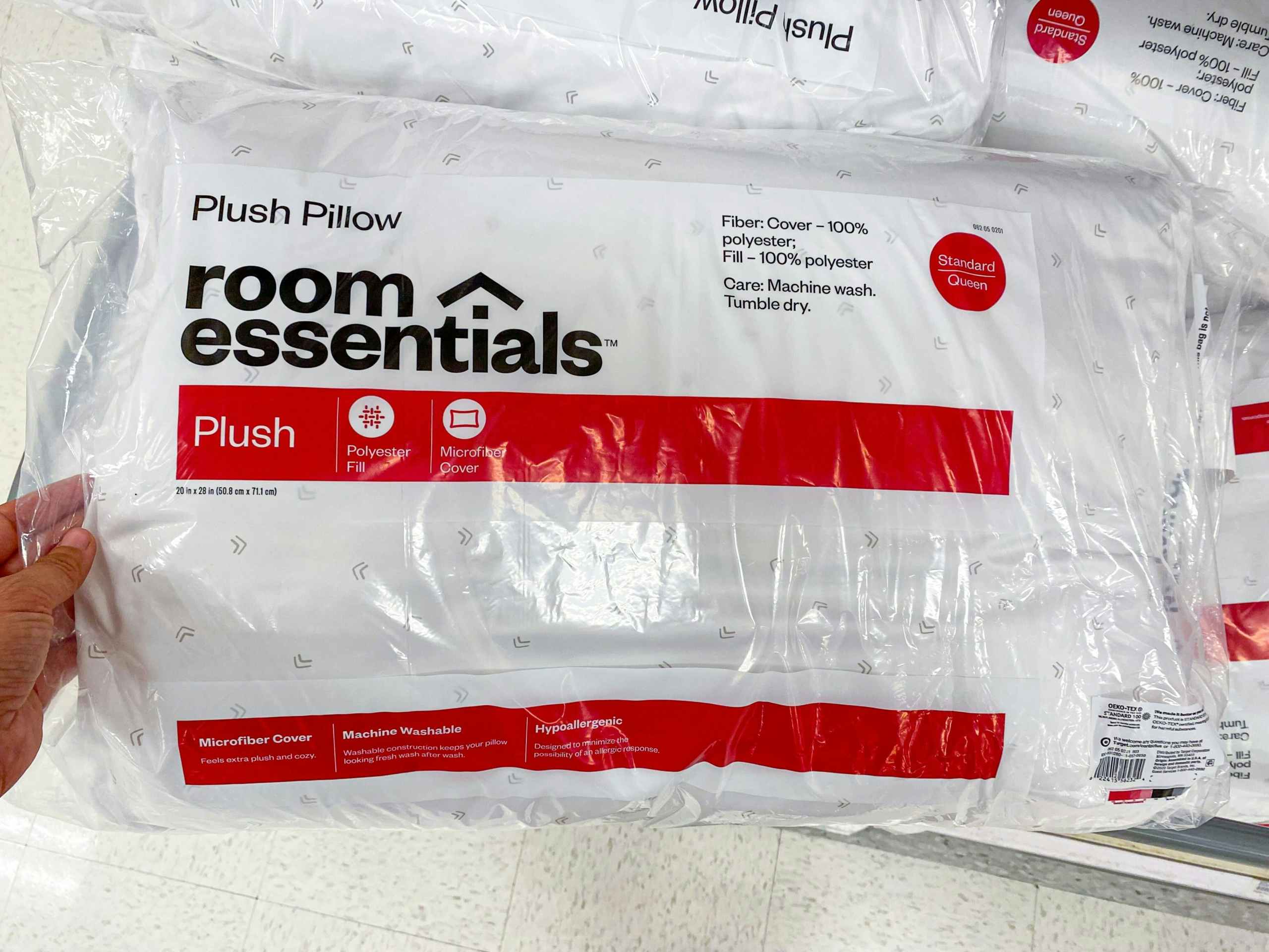 hand grabbing a room essentials plush bed pillow off a target shelf