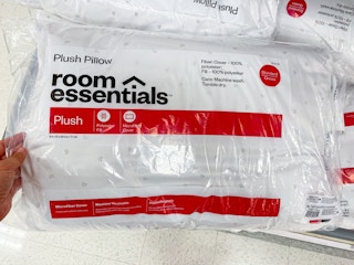 hand grabbing a room essentials plush bed pillow off a target shelf