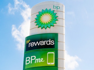 A sign next to a BP gas station advertising the BPme rewards app.