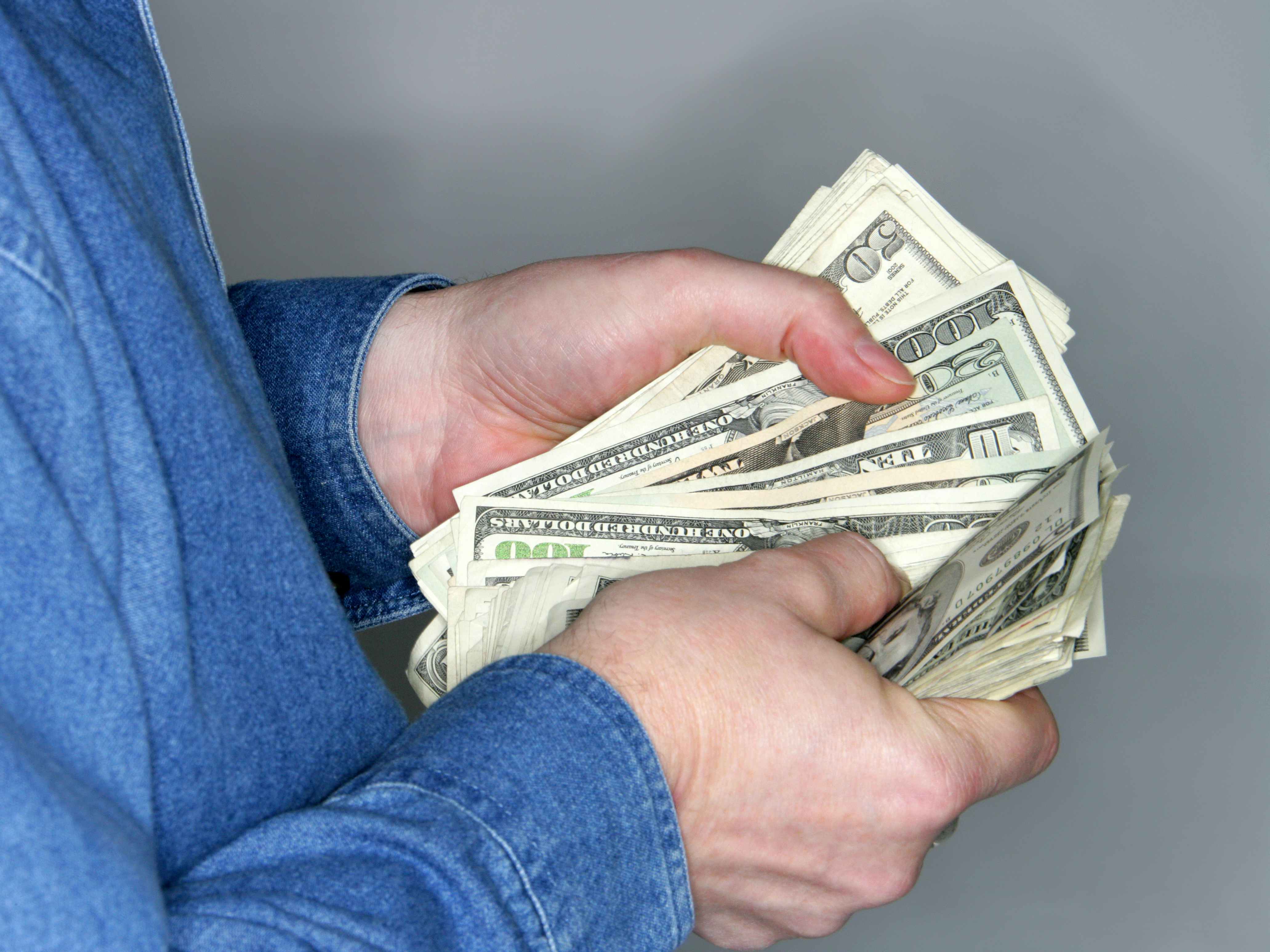 A person counting a handful of cash.