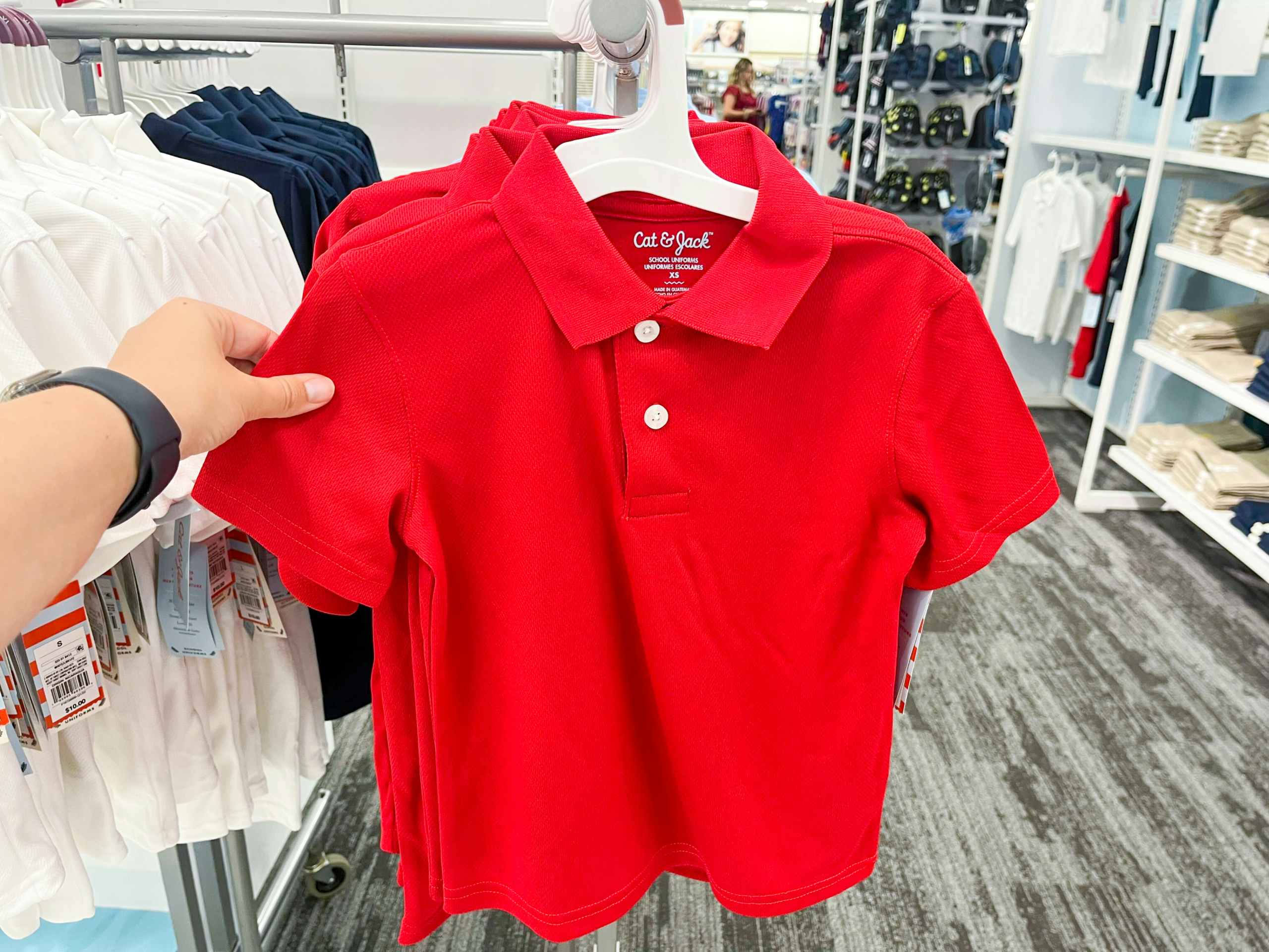 hand grabbing a polo off of the store display clothing rack