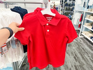 hand grabbing a polo off of the store display clothing rack