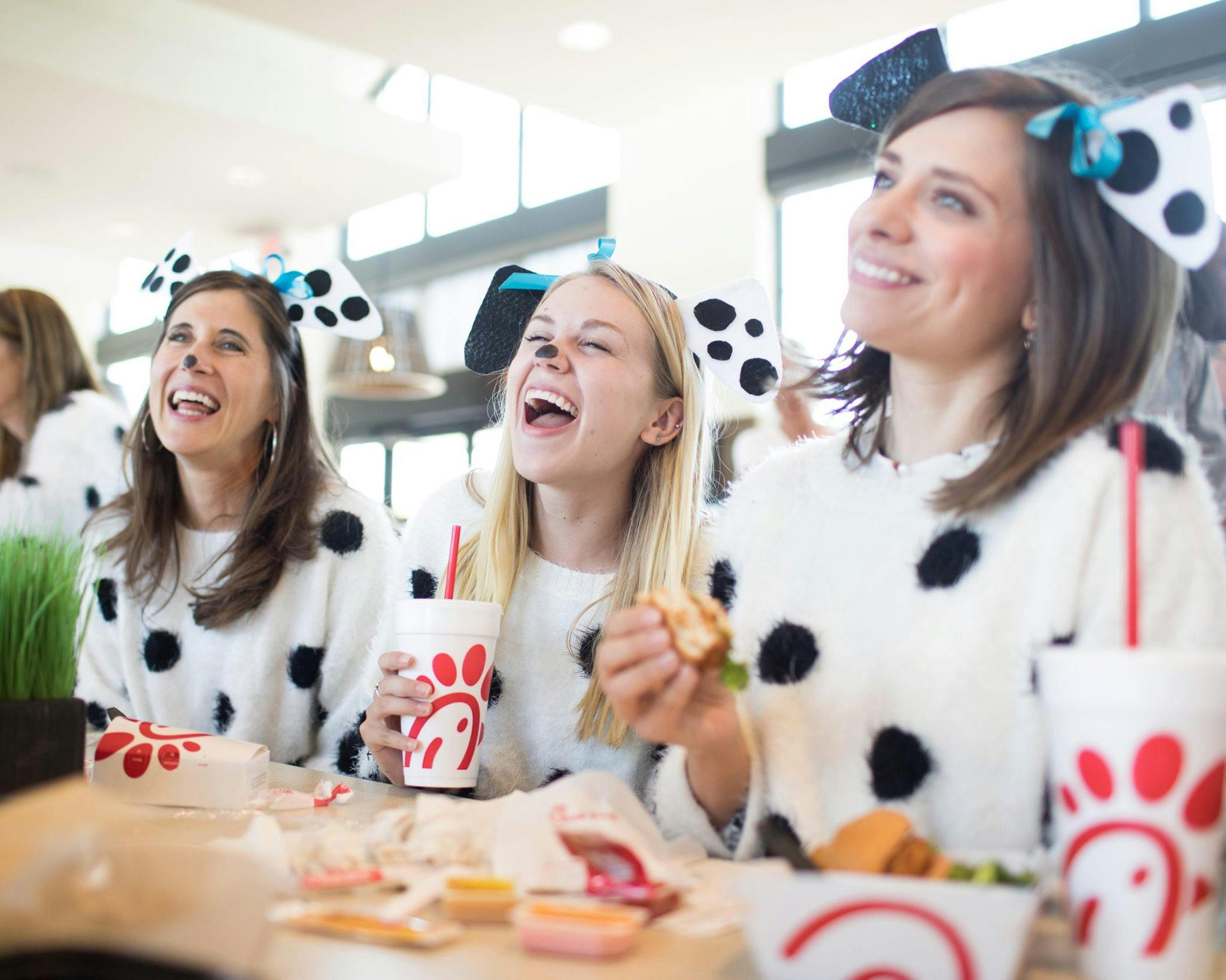 Three women eating chick-fil-a dressed like cows
