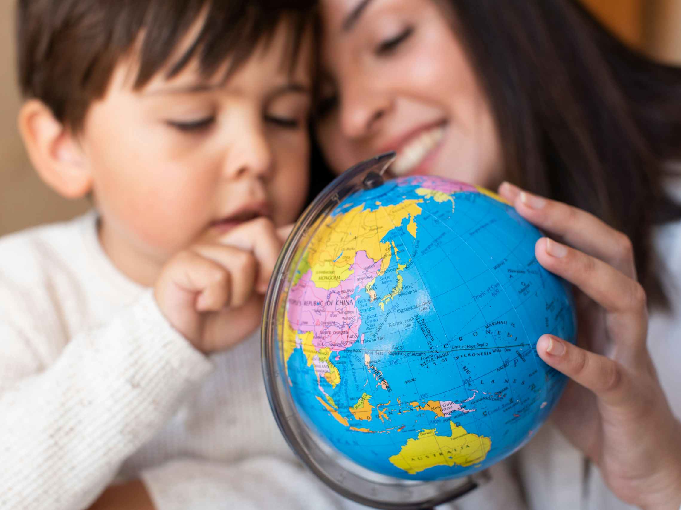 A child and parent looking at a globe together.