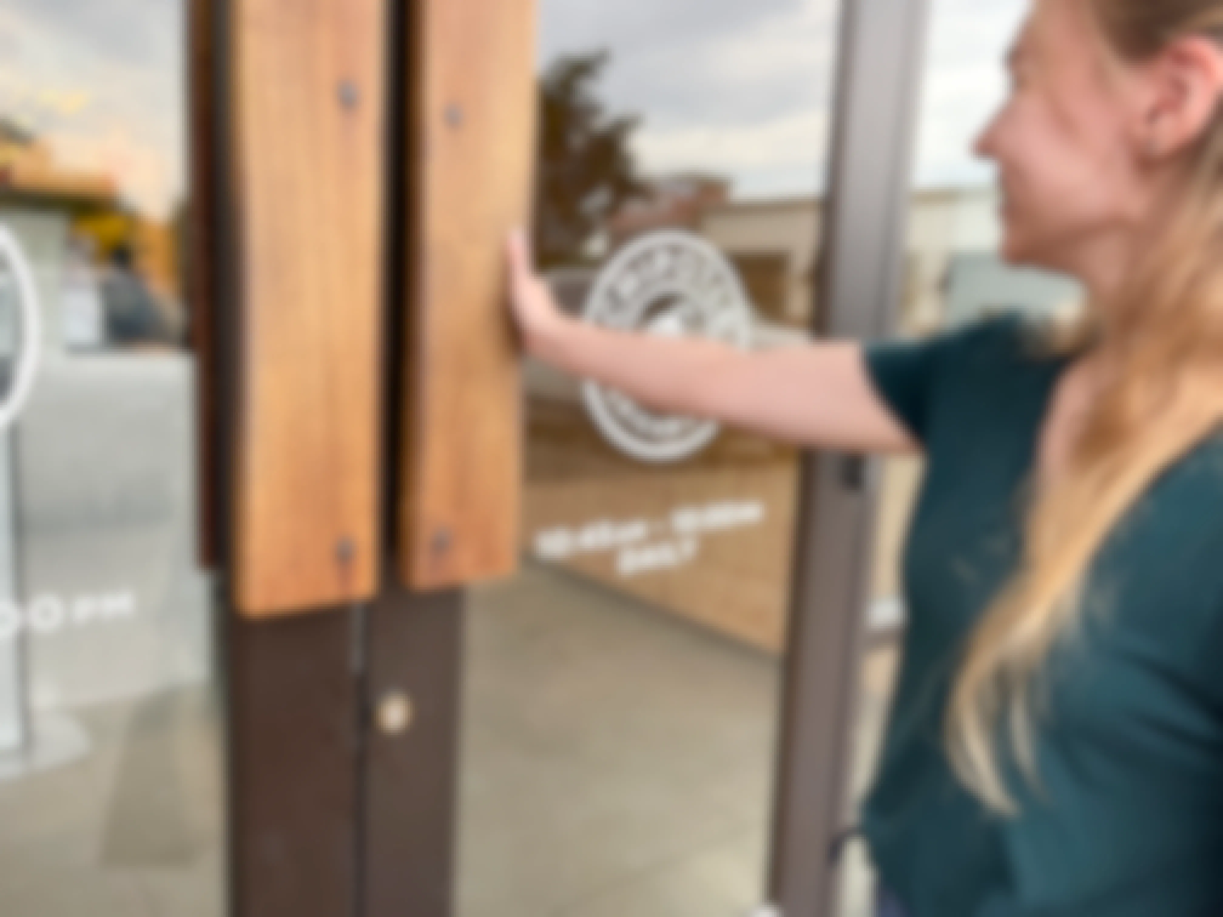 A woman opening the door to enter a Chipotle restaurant.