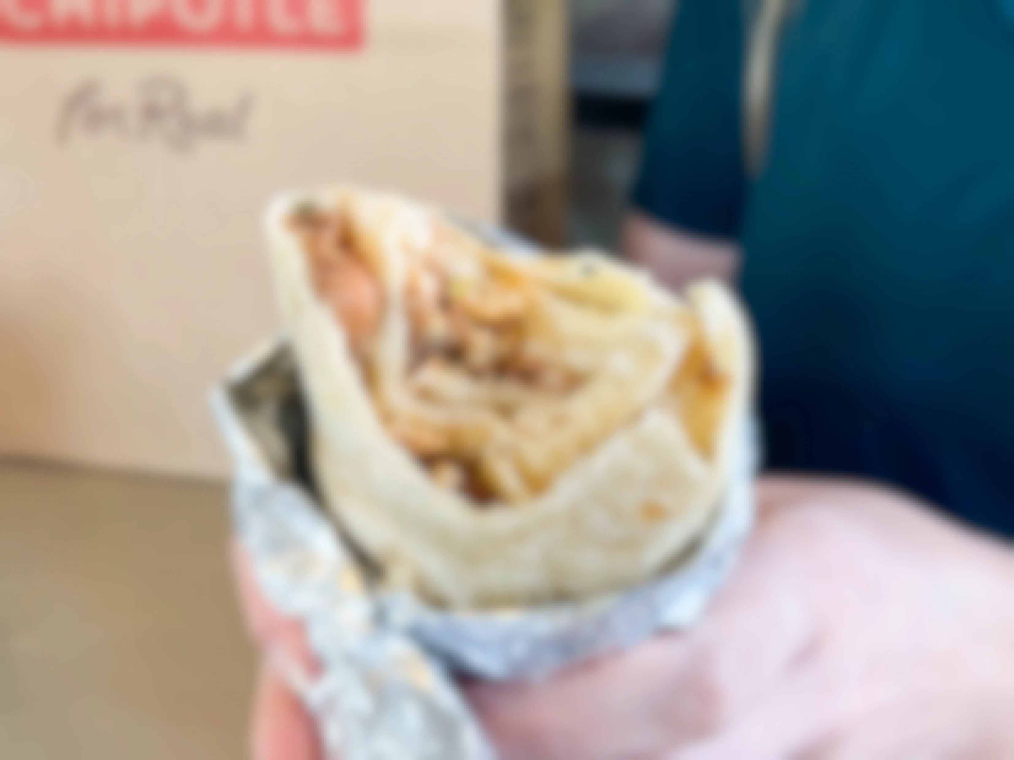 A person holding a chipotle secret menu burrito that has bitten into. The beans chicken and rice are visible inside.