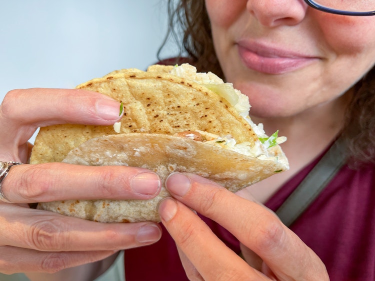 A person picking up a chipotle secret menu soft shell taco with a hard shell taco inside.