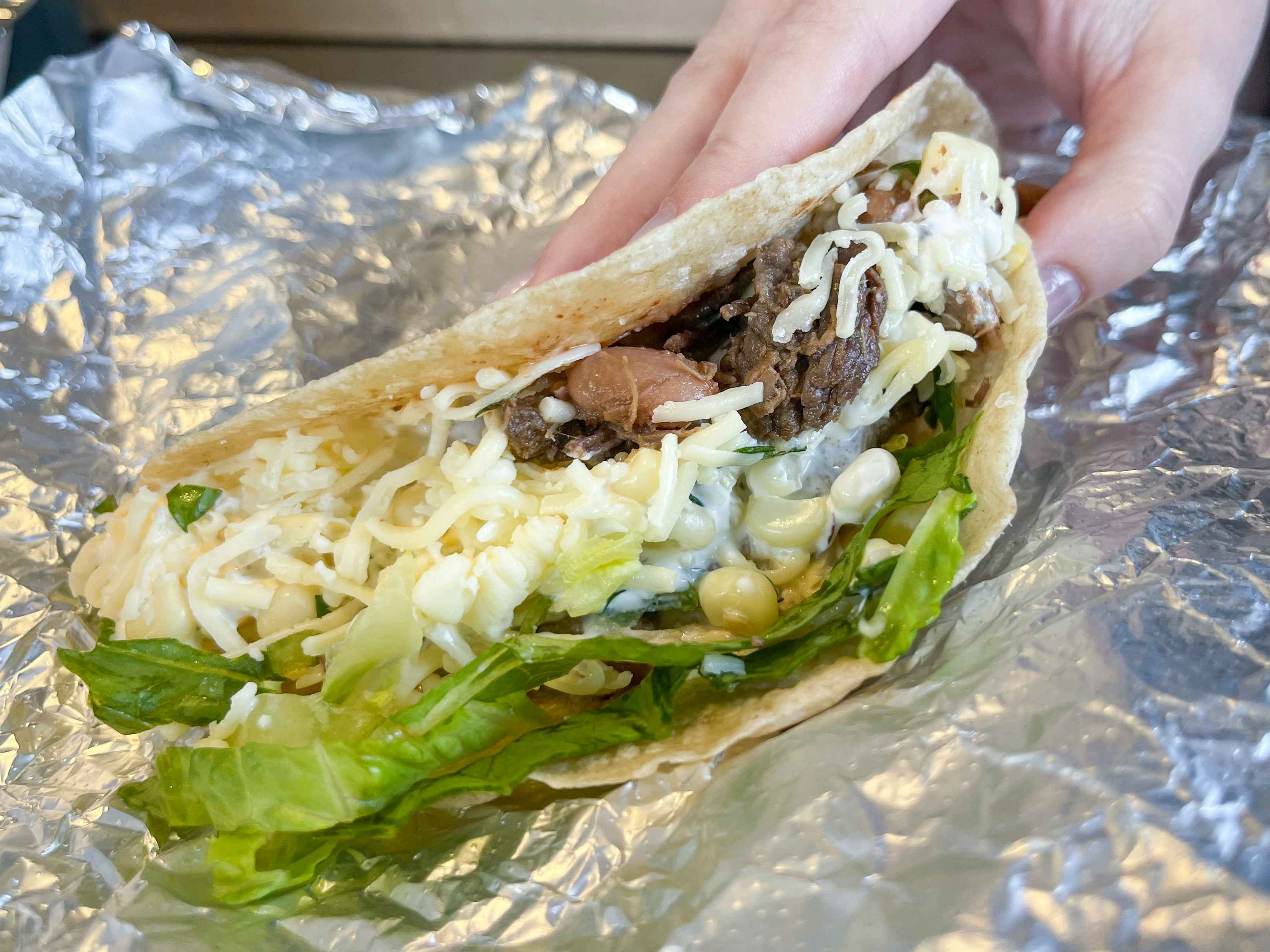 A person picking up a single taco.
