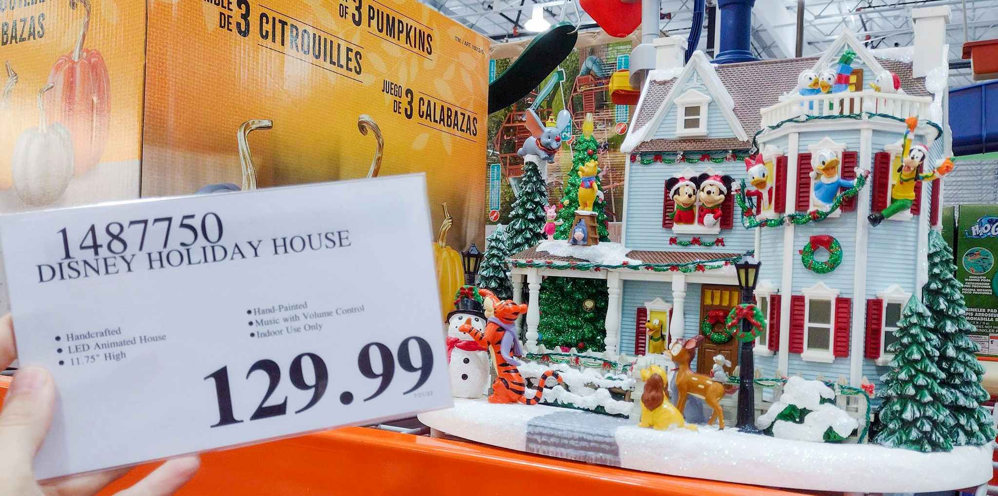 disney holiday house on a shelf at costco. sales tag held in hand.