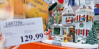 disney holiday house on a shelf at costco. sales tag held in hand.
