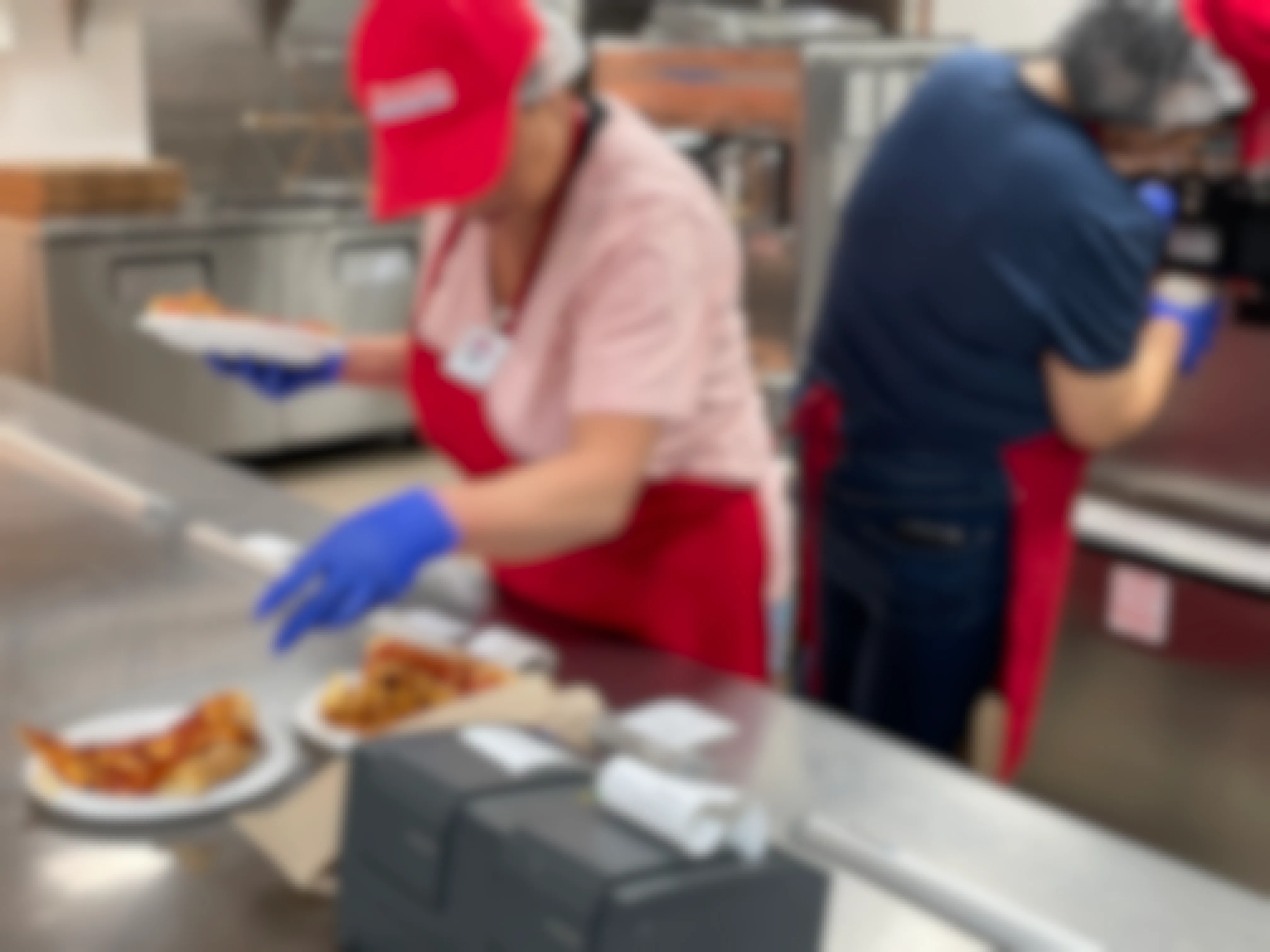 Costco employees preparing an order of pizza slices at the Costco food court