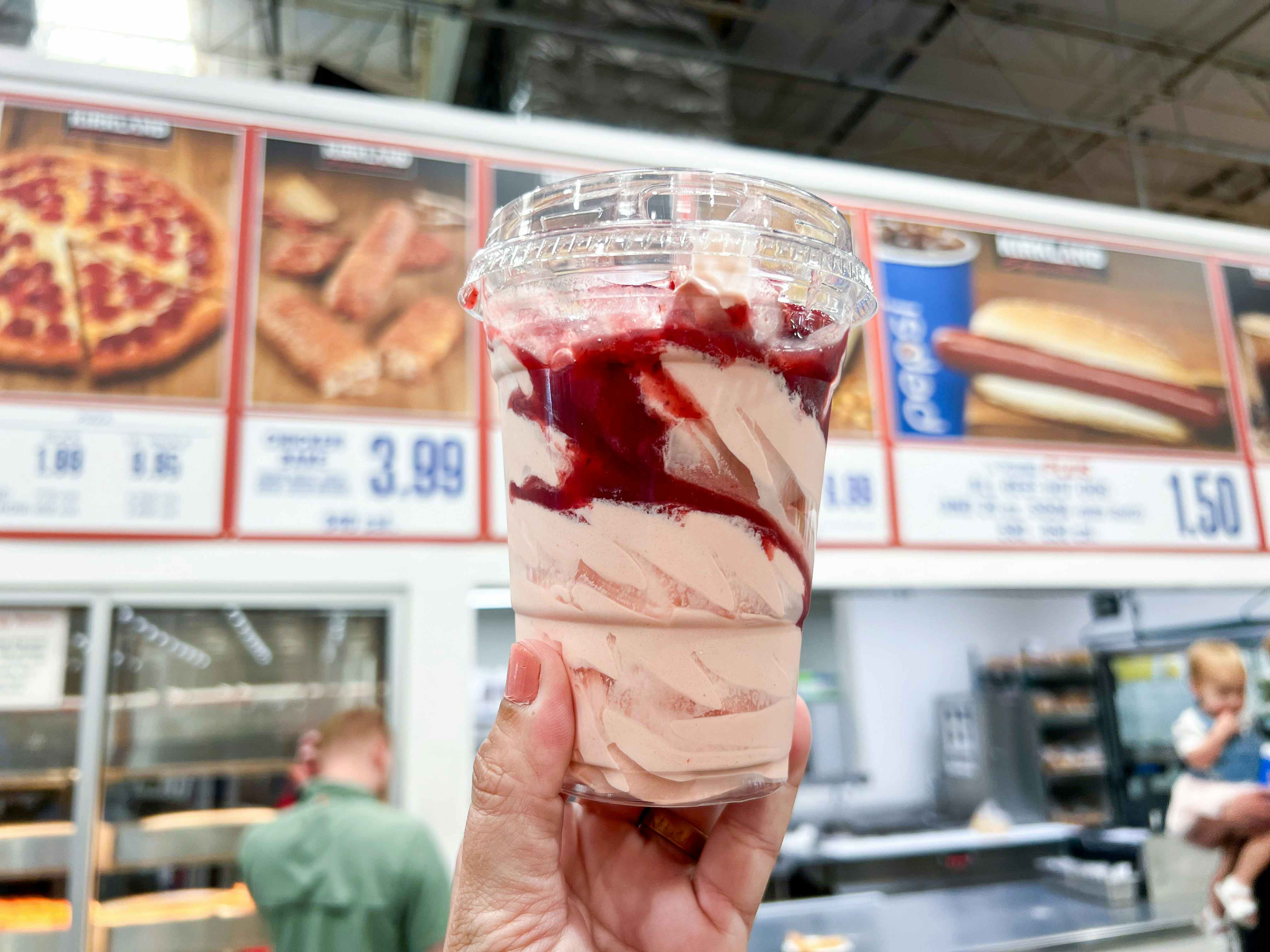 a person holding a costco ice cream sundae