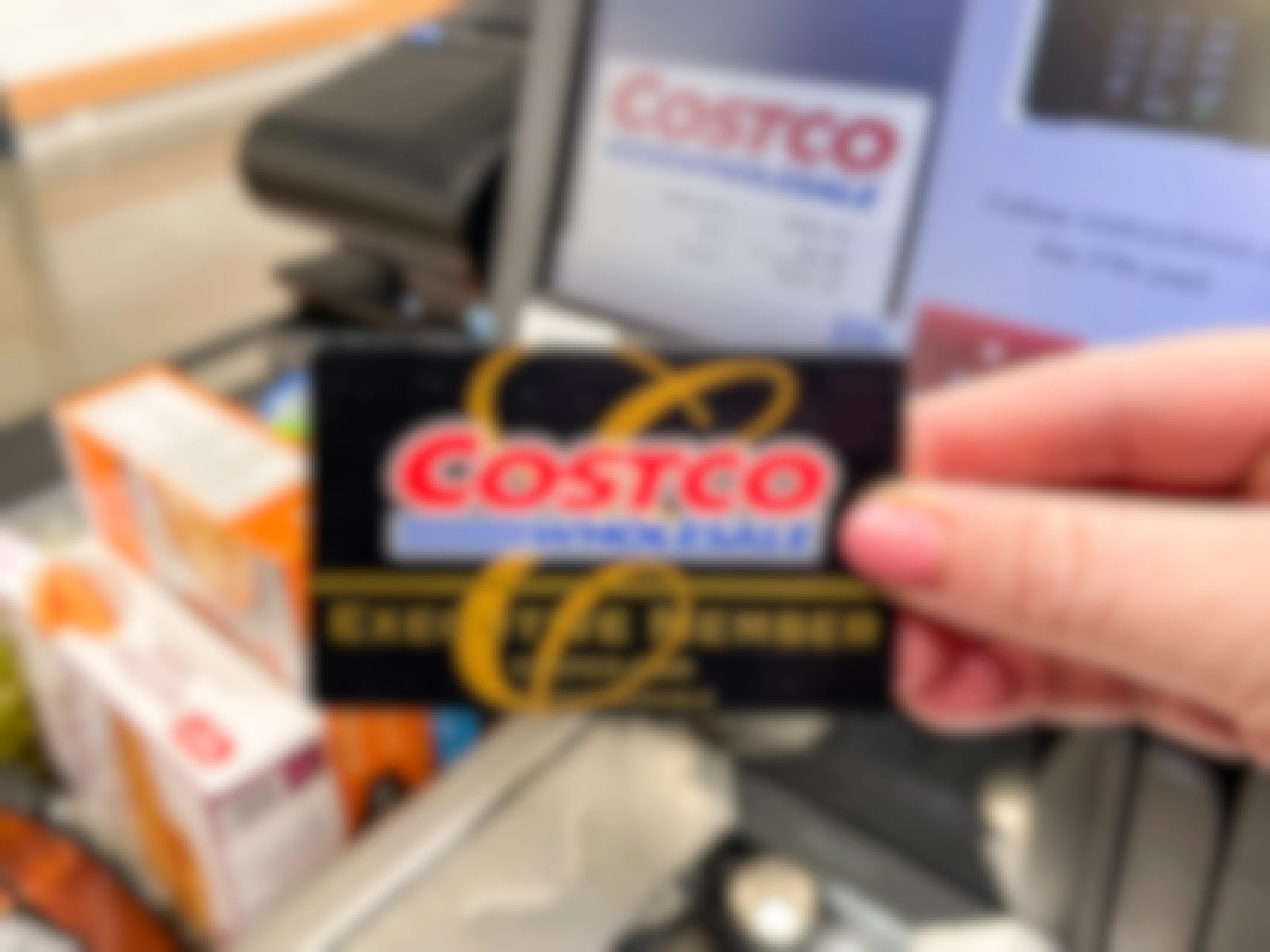 A person's hand holding up their Costco membership card in front of the self-checkout scanner at Costco.