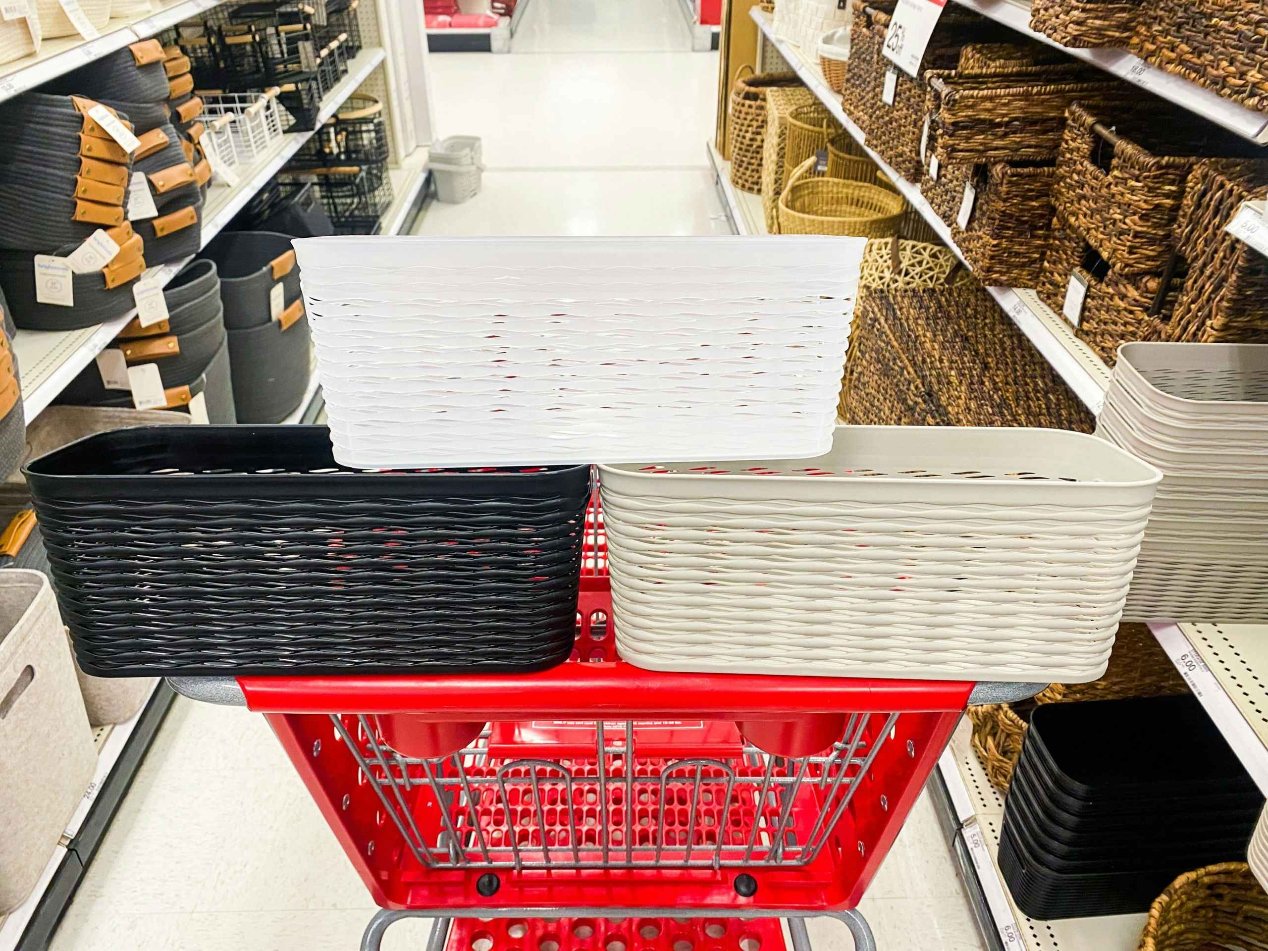 Three decorative storage baskets in a Target shopping cart next to other storage baskets on shelves