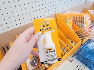 hand holding a bottle of bic correction fluid