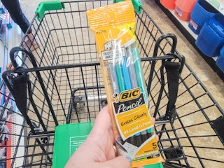 hand holding a pack of bic mechanical pencils over a cart
