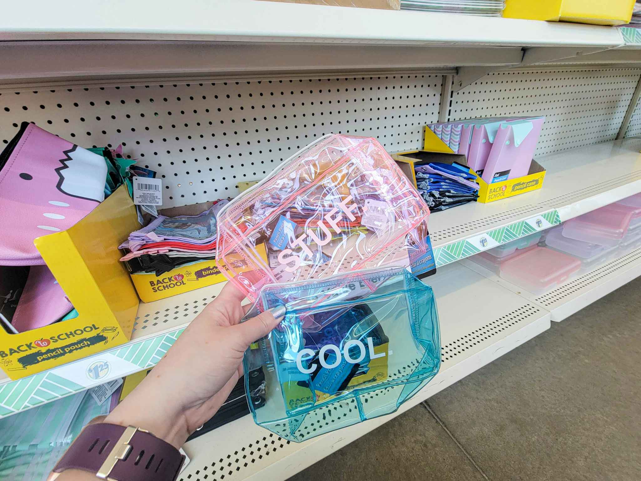 hand holding translucent pencil pouches, one pink that says stuff, one blue that says cool