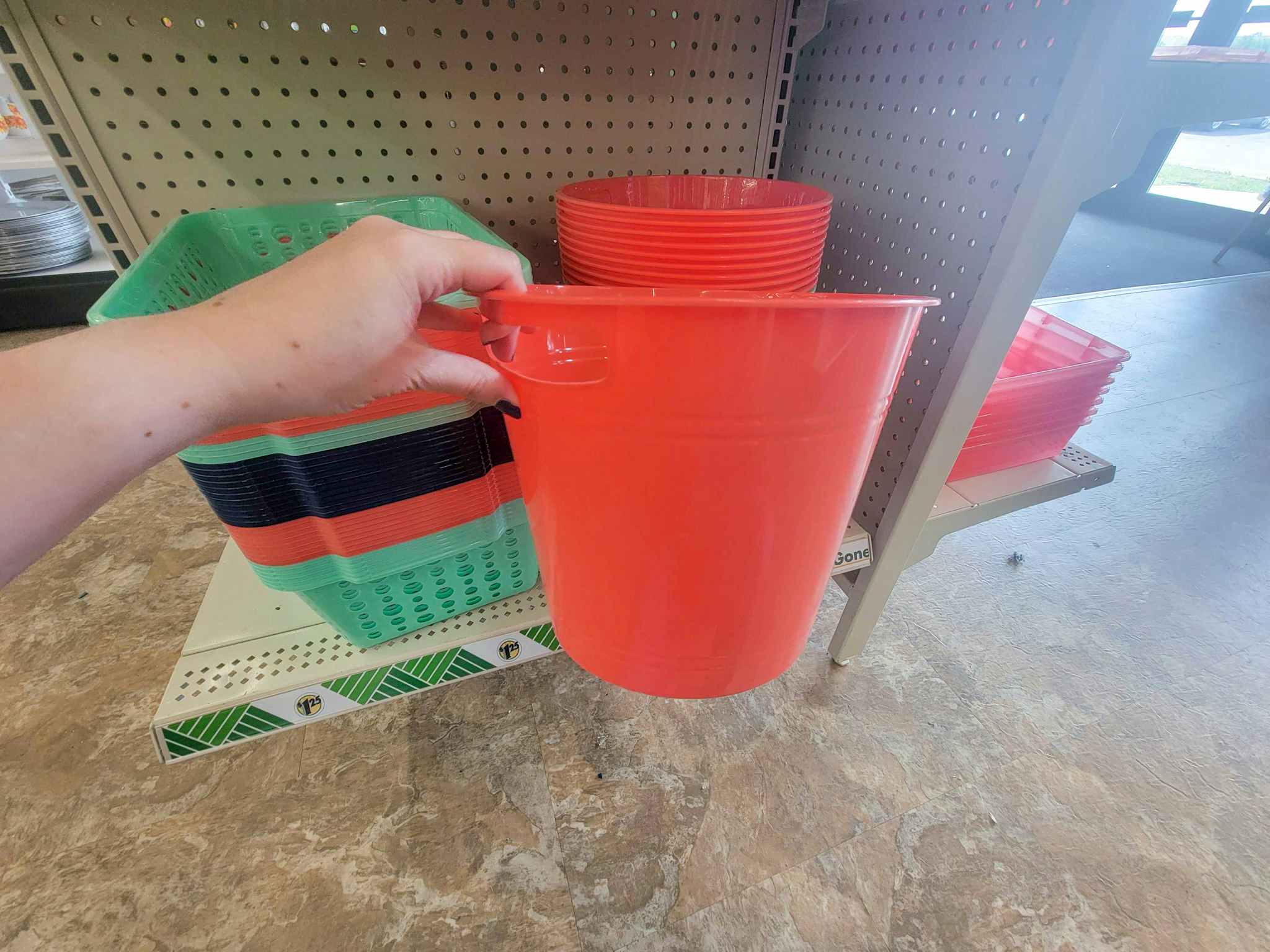 hand holding a small coral trash can size basket