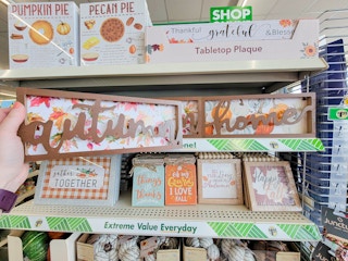 hand holding an autumn fall decor sign