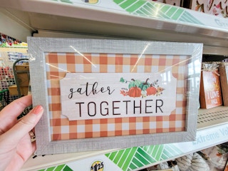 hand holding a fall sign that says gather together