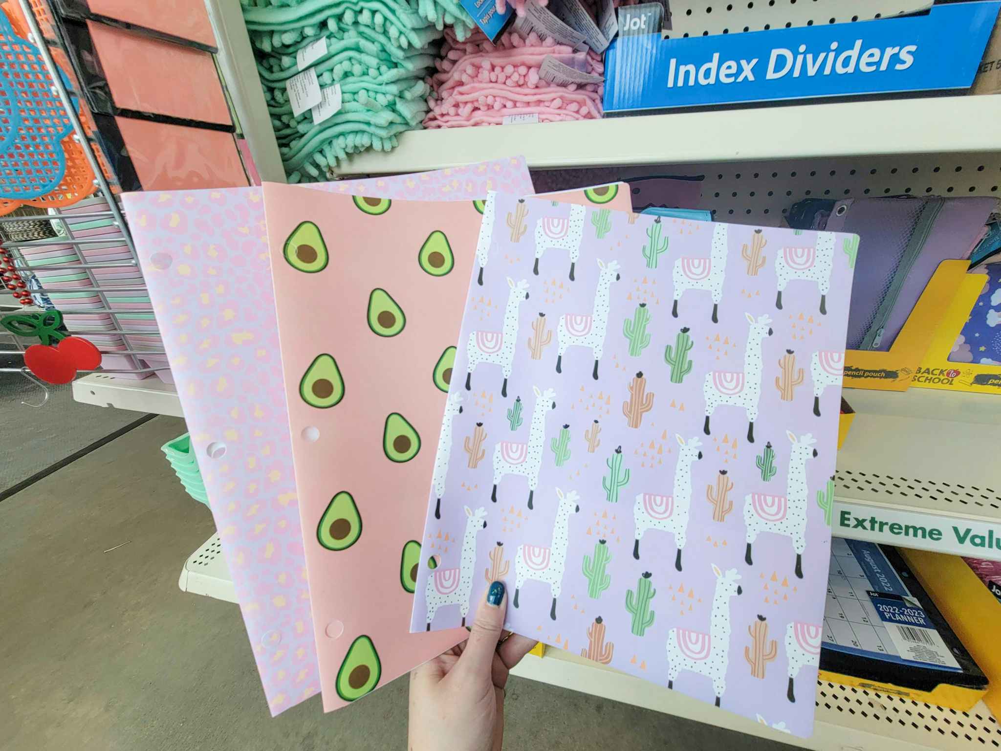 hand holding folders featuring avocados, llamas, and cheetah spots