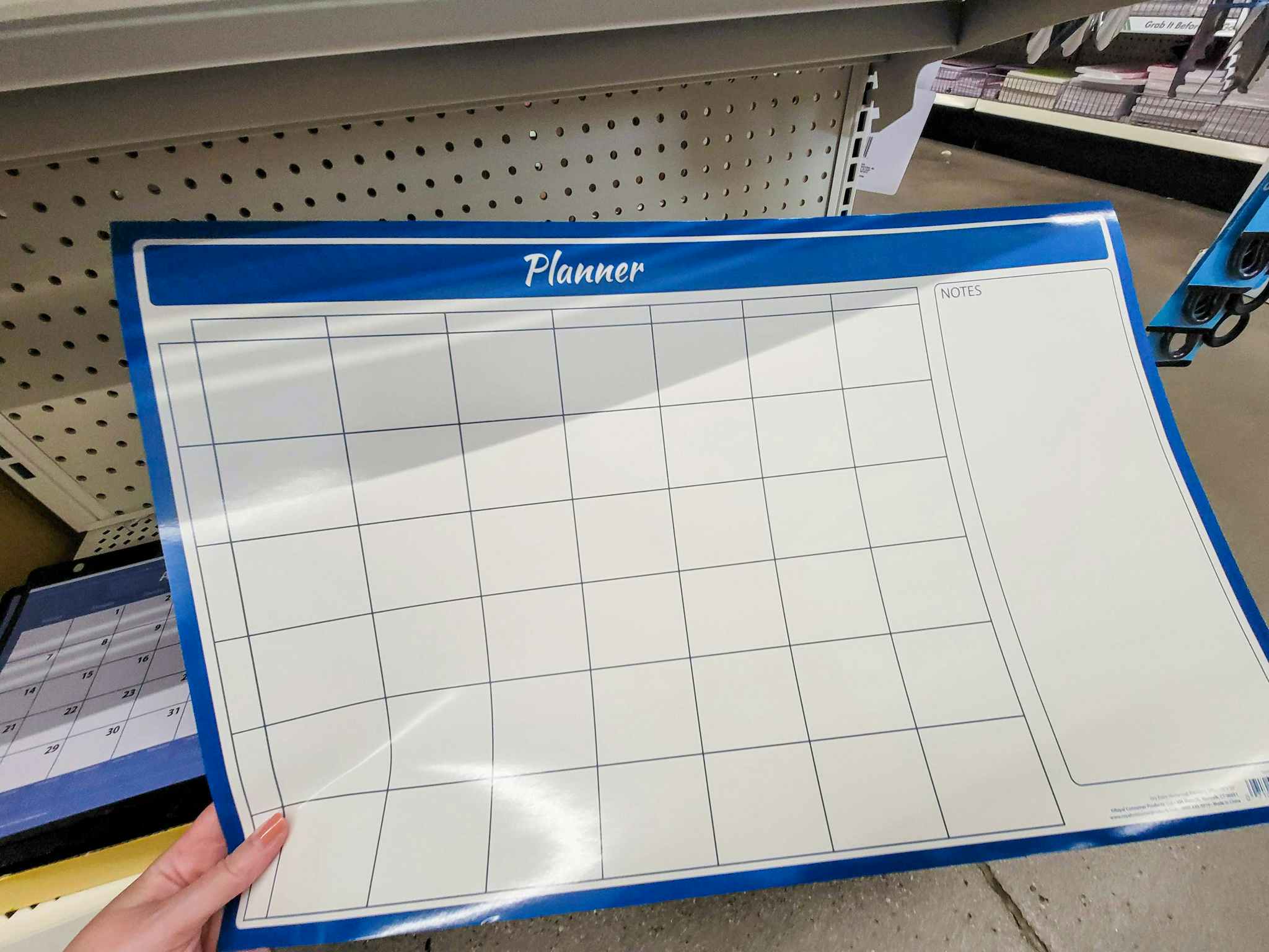 hand holding a large dry erase calendar planner