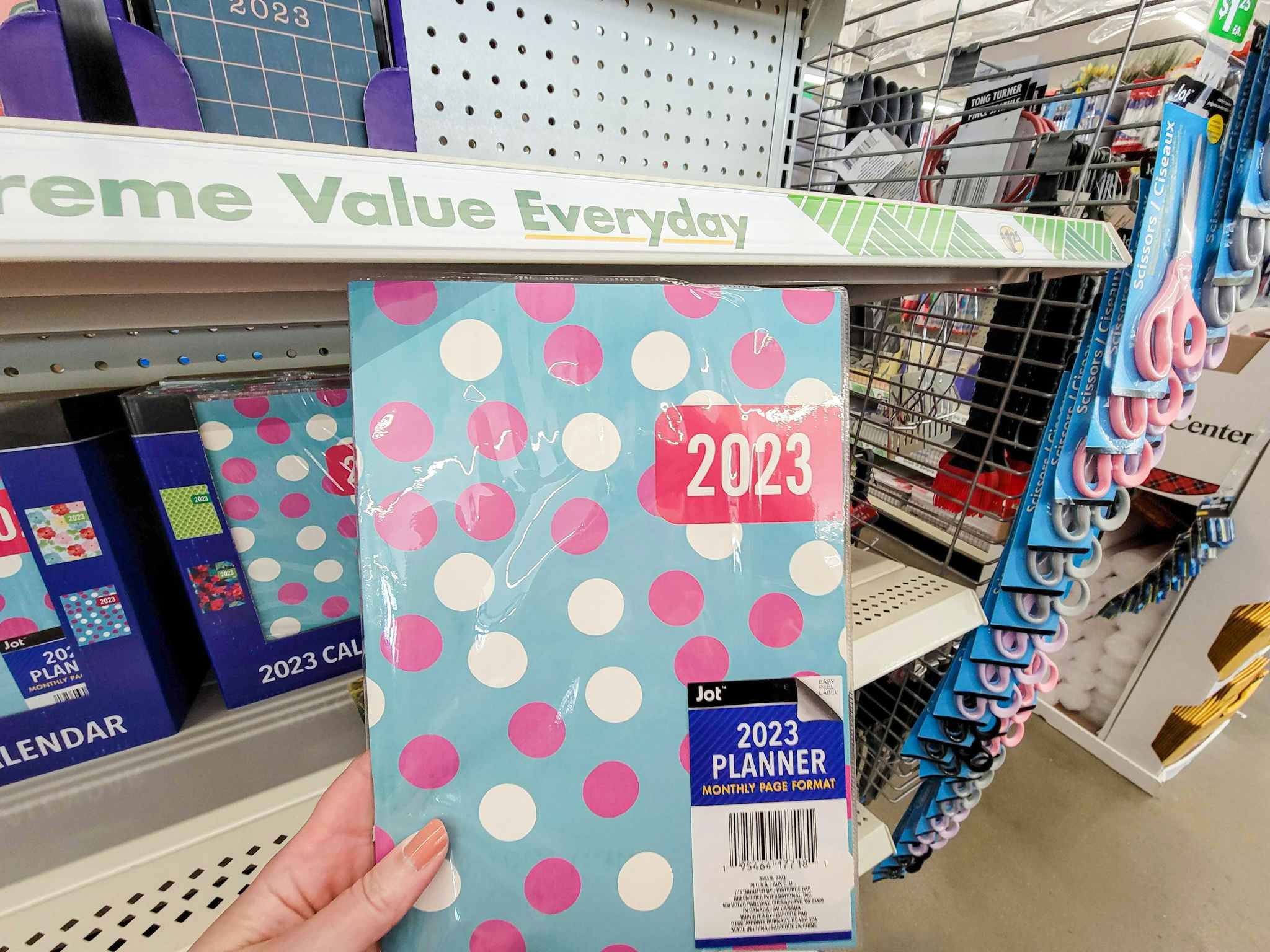 hand holding a 2023 planner, it's teal with white and pink polka dots