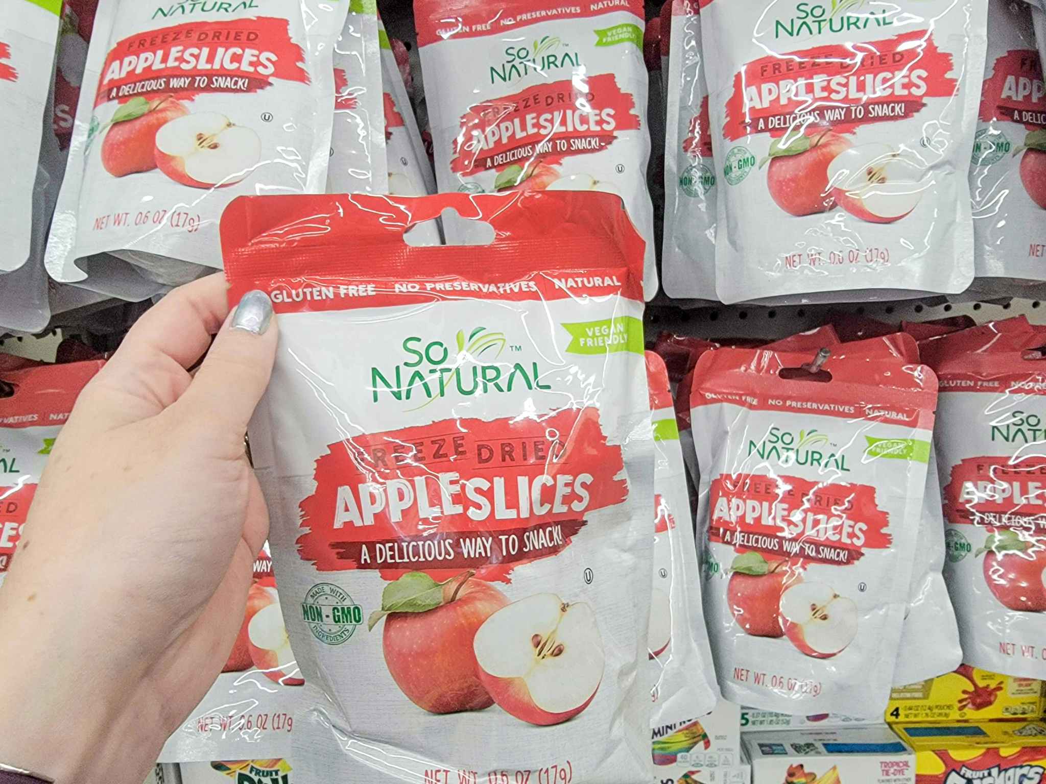 hand holding a pack of freeze dried apple slices